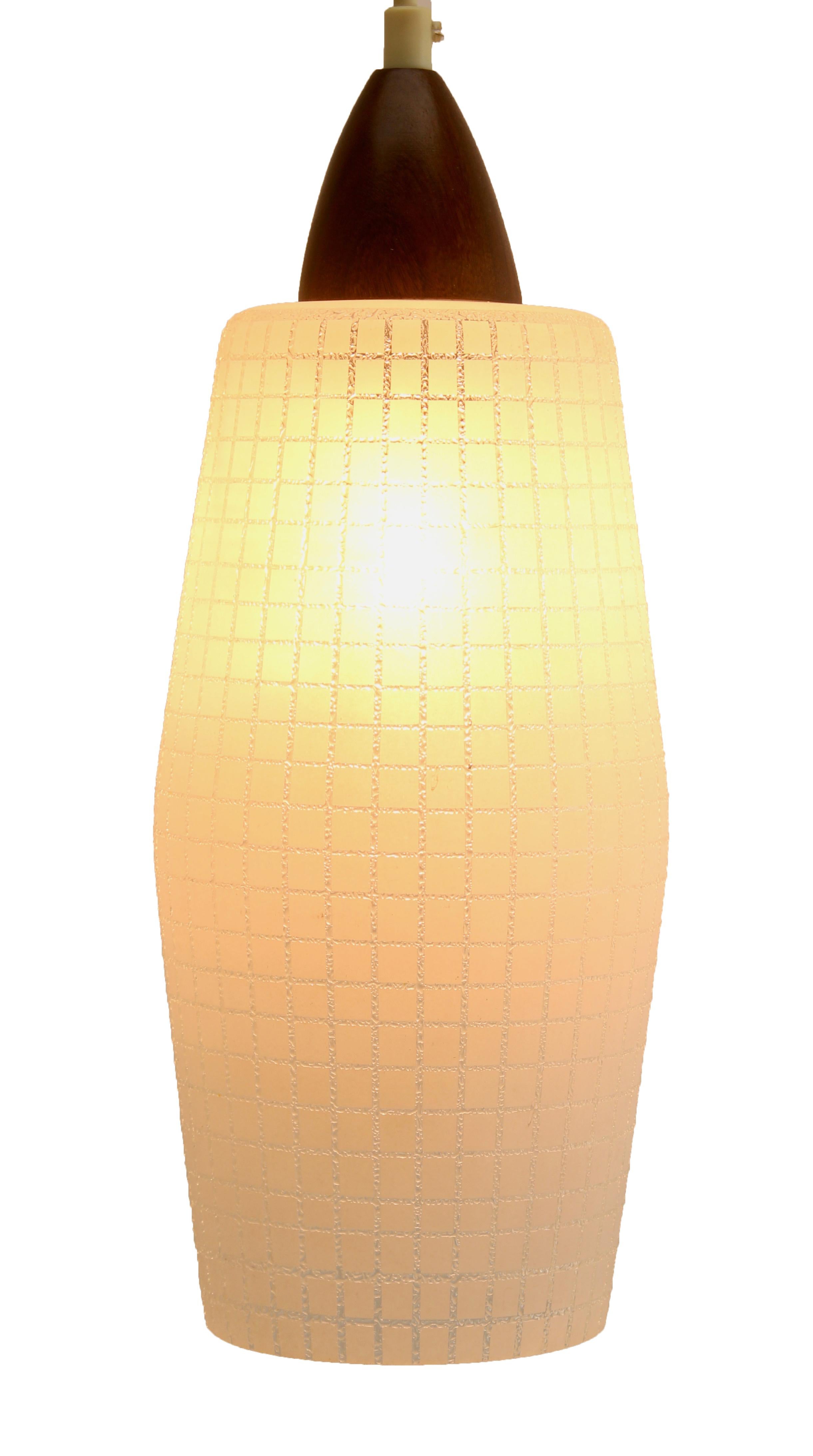 Hanging pendant light from the late 1950s on an adjustable cable, designed in the Scandinavian style with teak wood and a frosted, light-shade with grid pattern motief
Its Classic modernist form and simplicity in design, make it an iconic example