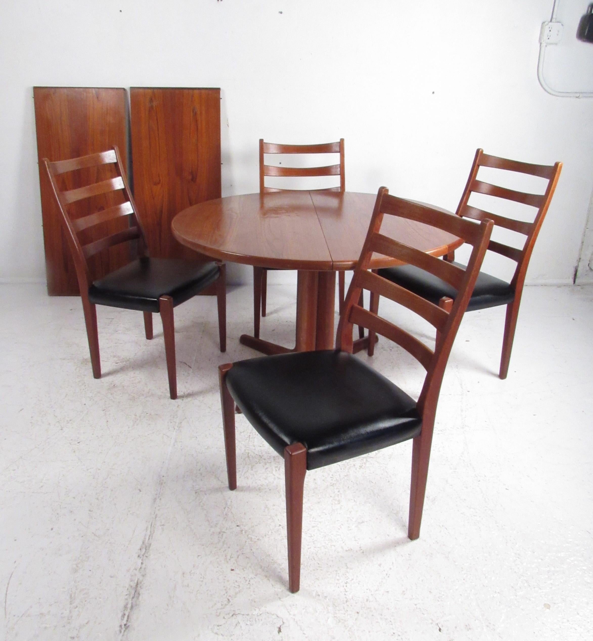 A stunning vintage modern Danish teak pedestal base dining table with two leaves by Skovby Mobelfabrik. This attractive set caters to many with the ability to expand from 46.5 inches to 85 inches wide. The sleek set of four dining chairs boast teak