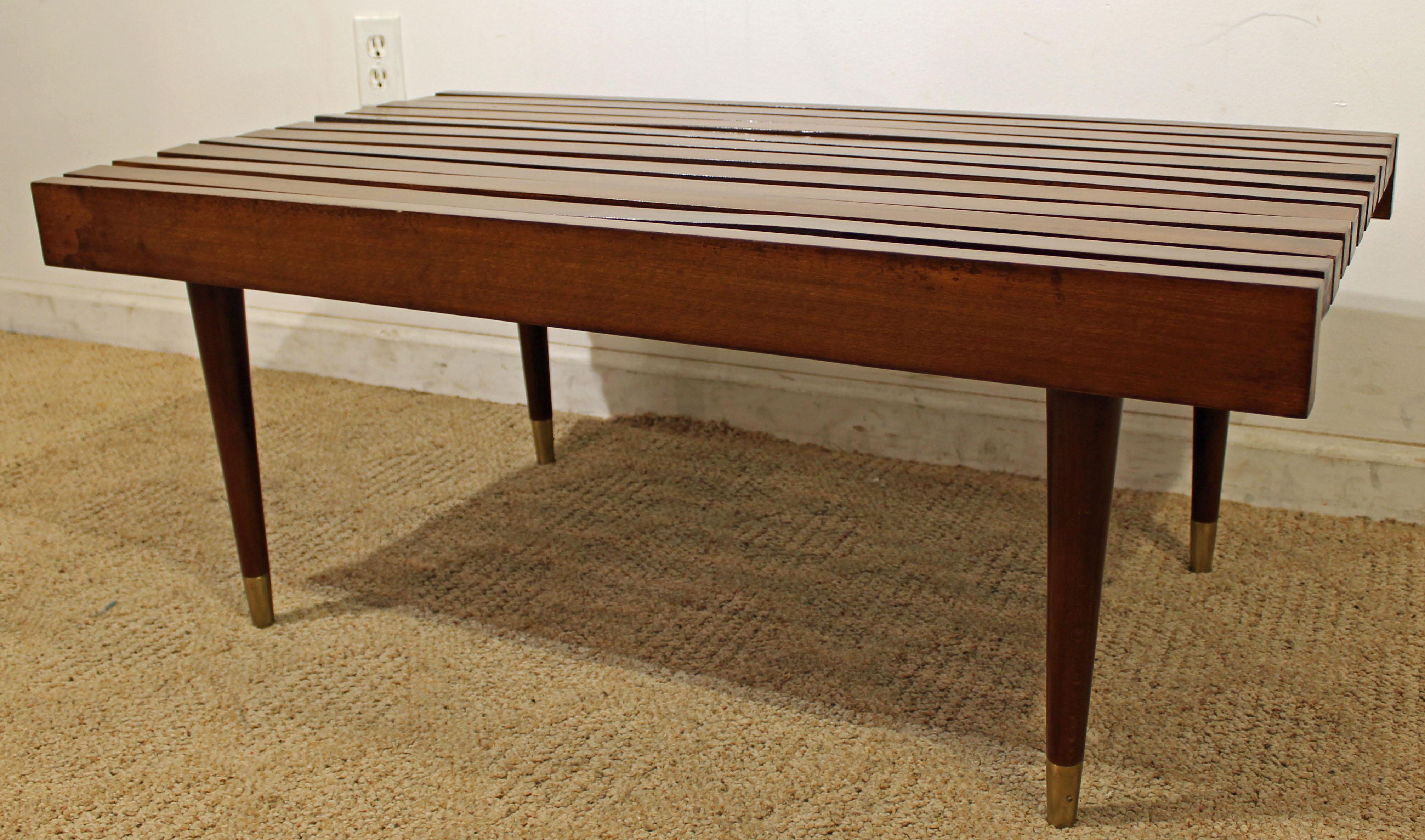 What a find. Offered is a midcentury coffee table. It is made of walnut with brass feet. The piece shows minor wear (minor surface wear/chips, some boards slightly warped, age wear-- see pictures) but nothing overly noticeable. It is not signed.