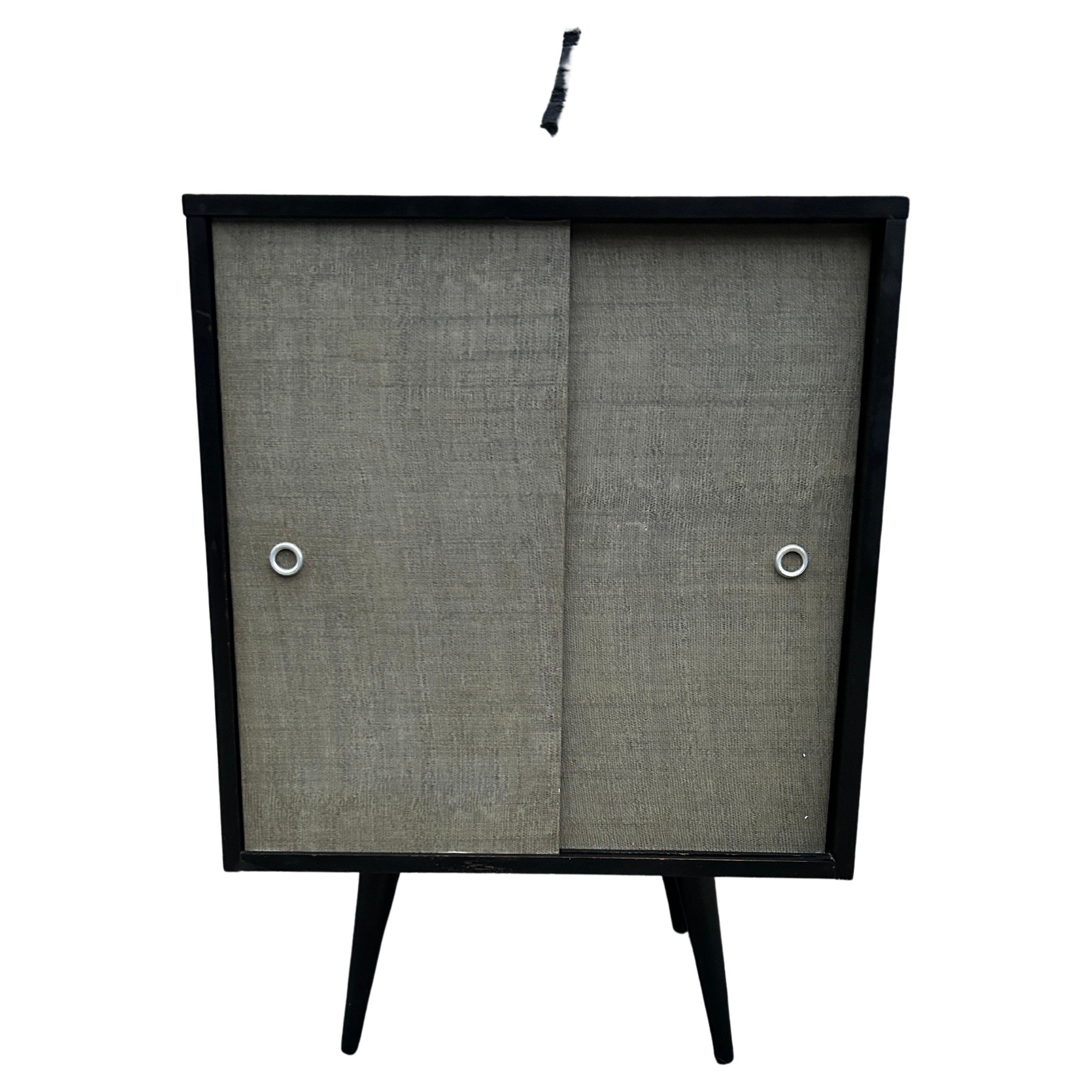 Beautiful mid-century small cabinet by Paul McCobb circa 1950 planner group #1512 has 1 fixed shelf - solid maple construction has original black lacquer finish. Has original seaweed light green sliding front doors with aluminum pulls sits on 4