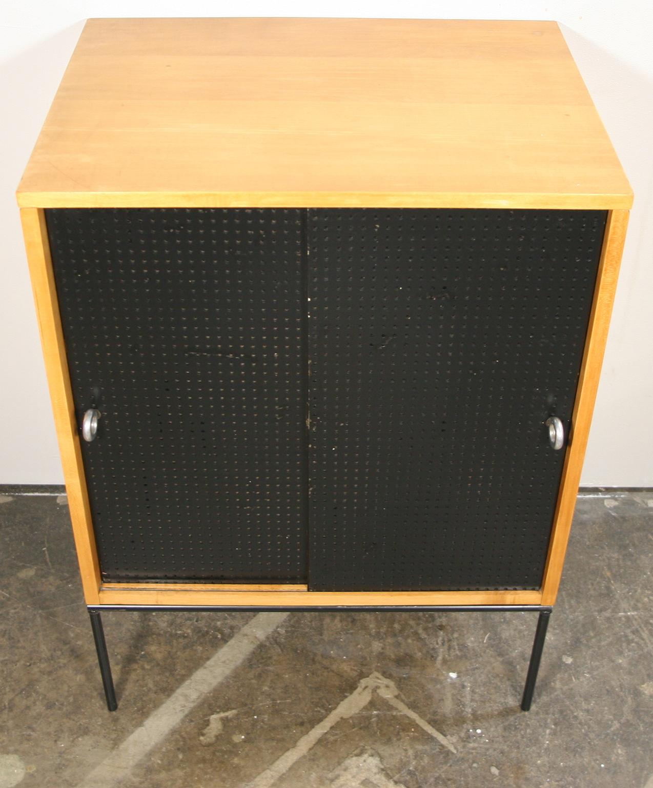 Beautiful midcentury small cabinet by Paul McCobb circa 1950 planner group #1512 has 1 shelve - solid maple construction has a blonde lacquer finish. Has very rare all original black fiberglass perforated sliding front doors with aluminum ring pulls