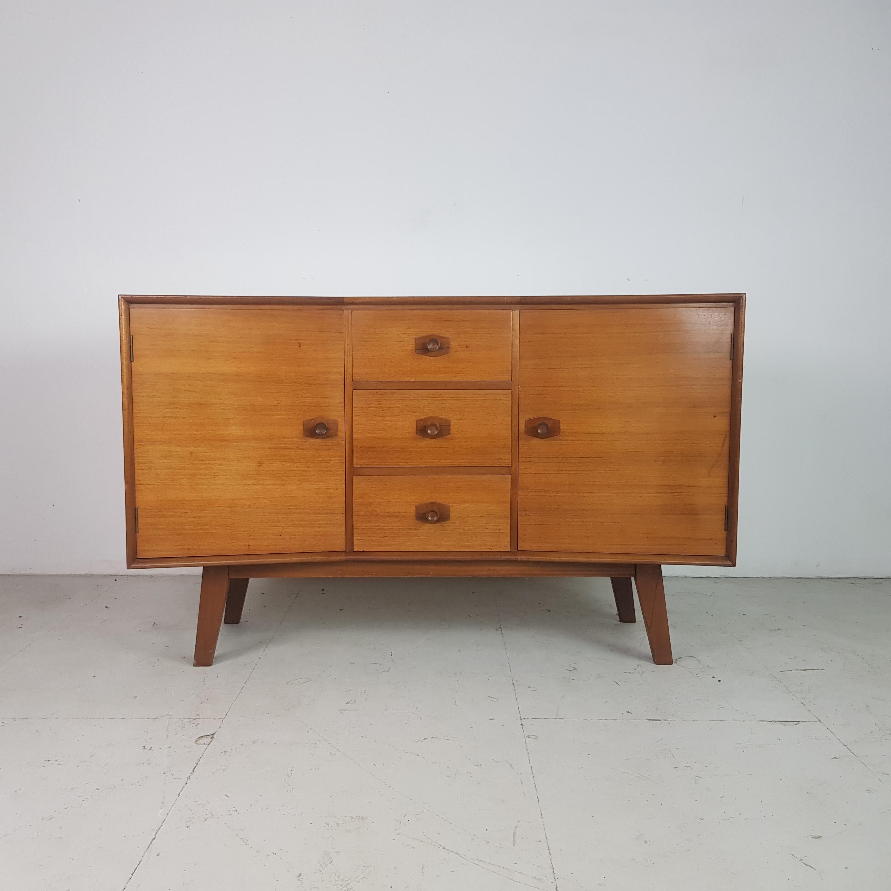 Lovely midcentury teak sideboard from heals with lovely angles.
In good vintage condition - it has been sanded and oiled.

Approximate dimensions:

Width 137cm

Depth 47cm

Height 87cm

Cupboards: 47cm x 36cm x 28cm.

Drawers: 33cm x
