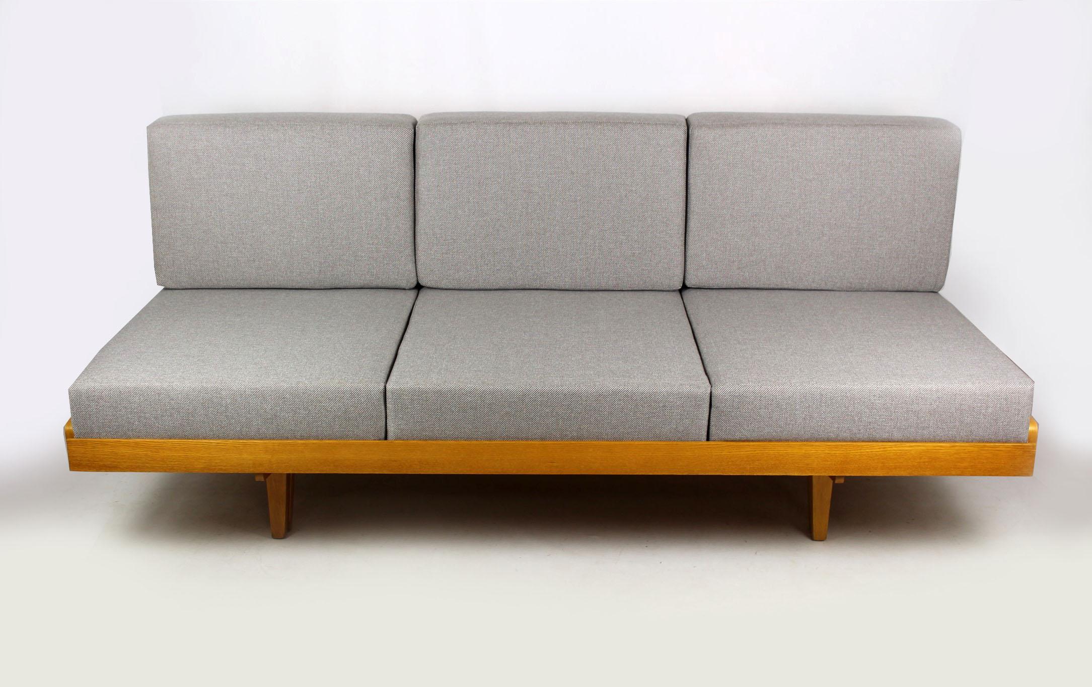 Midcentury sofa bed manufactured by Jitona in the 1960s. Made of ash veneered wood. The couch has been renovated, with restored woodwork, and new pillows upholstered with fabric that is resistance to dirt and abrasion. The couch can be simply