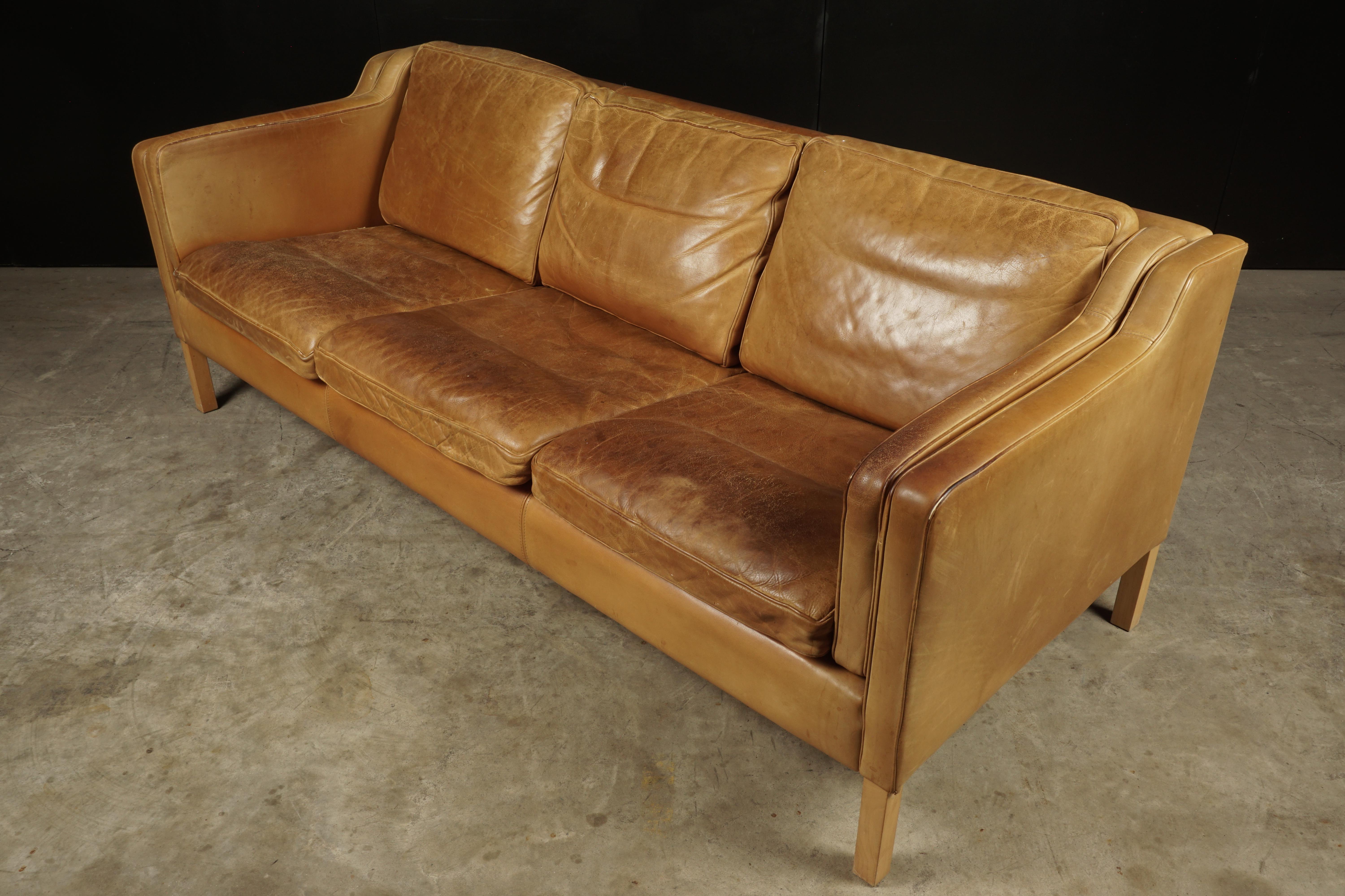 Midcentury sofa from Denmark in cognac leather, circa 1970. Three-seat with superb patina and wear.