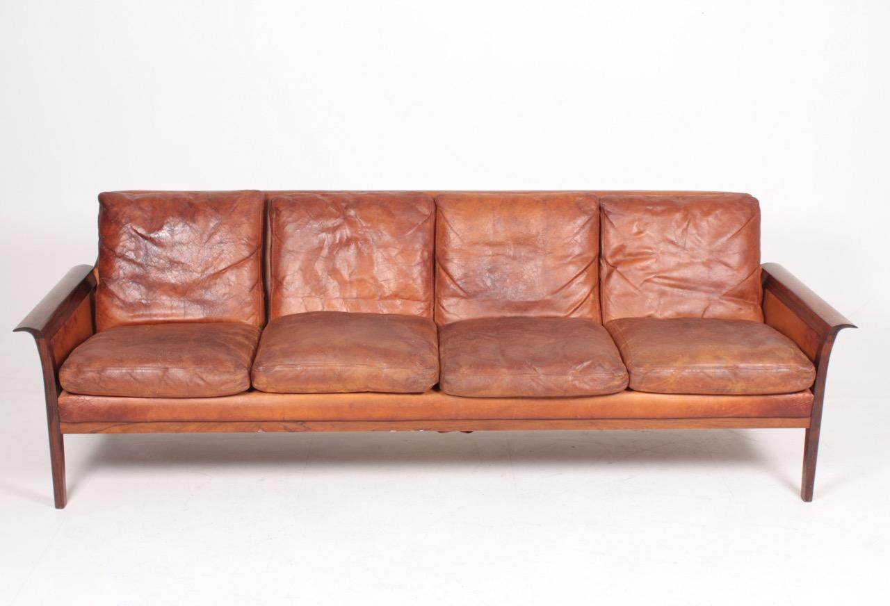 Sofa in patinated leather and rosewood designed and made in Denmark. Original condition.