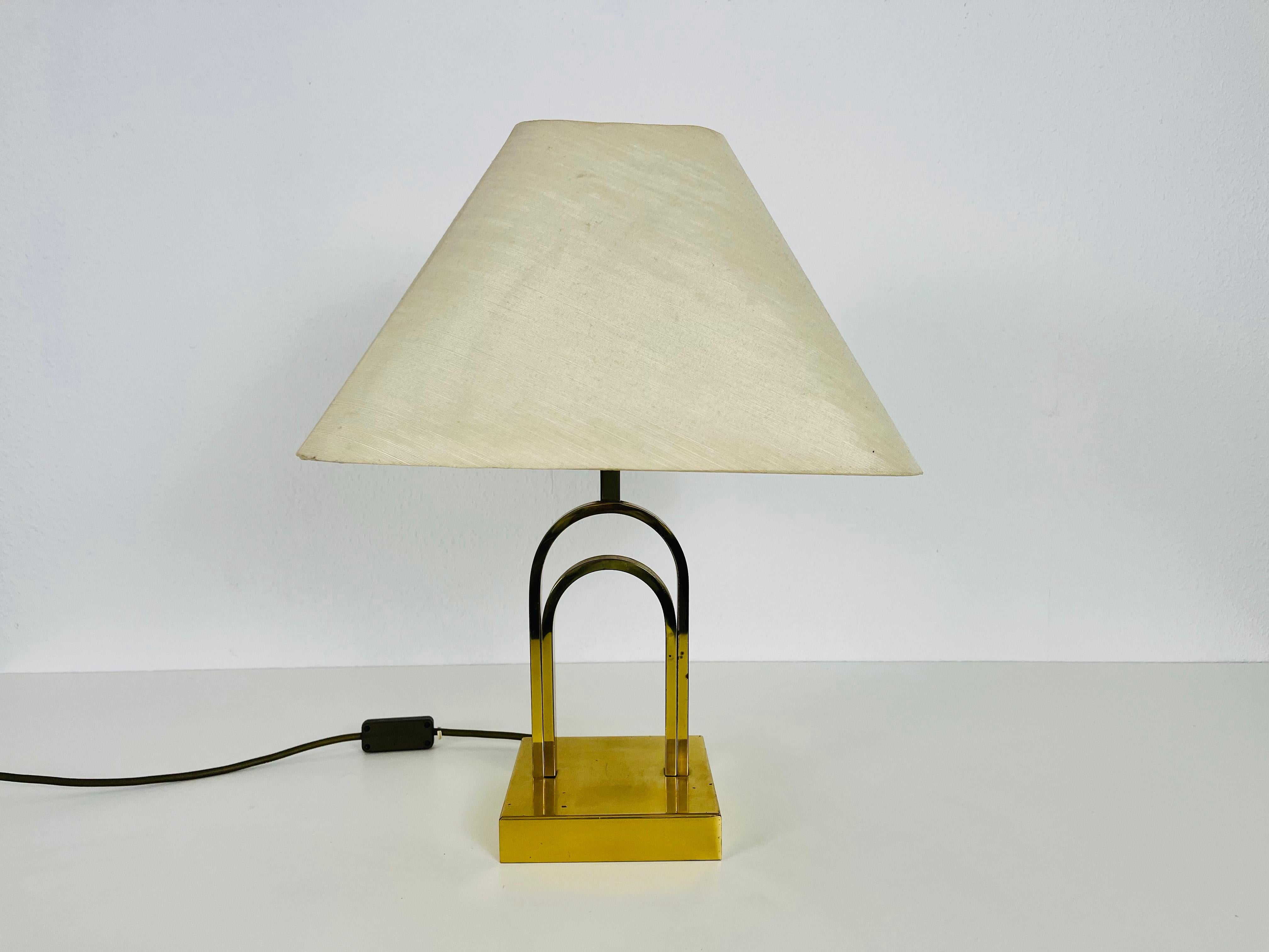 Une belle grande lampe de table fabriquée dans les années 1960. La base est en laiton massif. L'abat-jour est en tissu et a une couleur beige.

Le luminaire nécessite une ampoule E27. Fonctionne avec les deux 120/220 V. Bon état