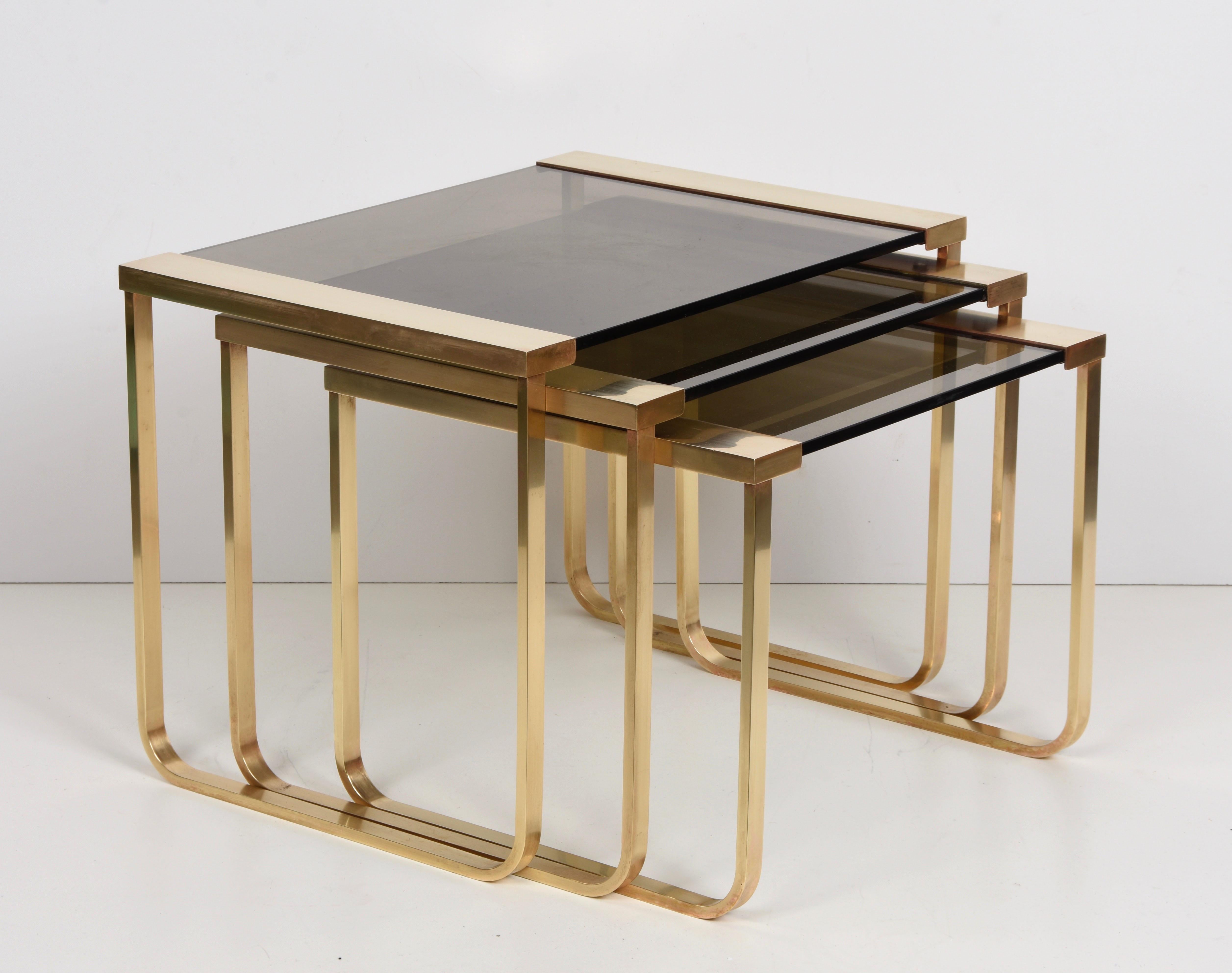 Amazing set of three interlocking tables in brass and smoked glass. This beautiful set was produced in France during 1970s.

These items of three nesting table are very adaptable and handy. Materials are breathtaking too, with solid brass and