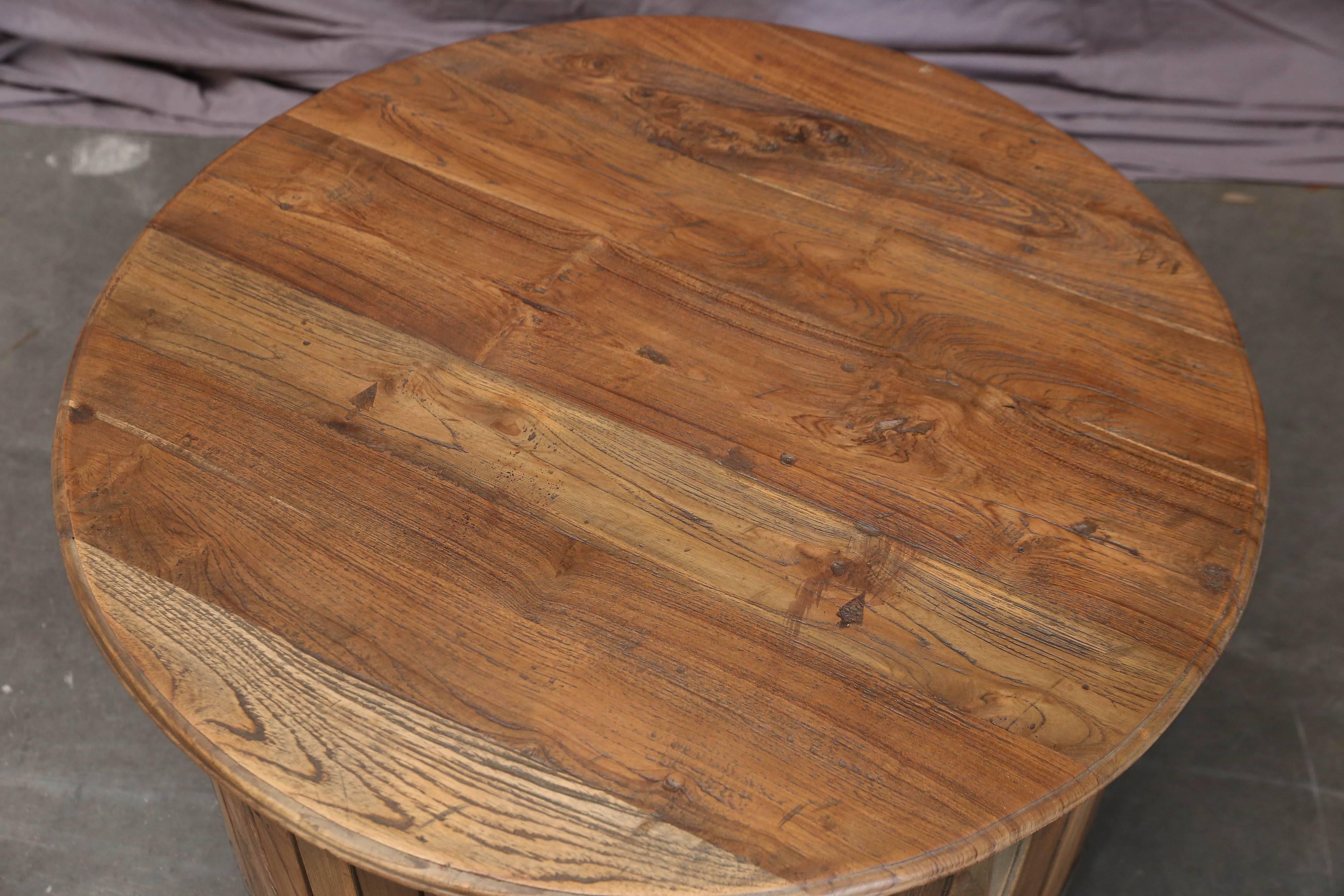 This solid teak wood round cocktail table is painstakingly handcrafted from hand picked old beams. The planks holding the tabletop is firmly held by two steel rims one in the top and the other at the bottom. It will be a charming addition to the