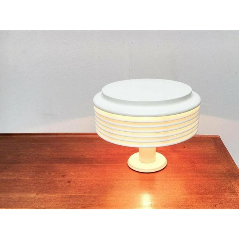 Rara versione della lampada da tavolo Saturno von Staff su progetto del designer giapponese Kazuo Motozawa degli anni Settanta. Qui nella rara versione in bianco.

L'elemento più evidente dei design Saturno sono le lamelle che formano il corpo