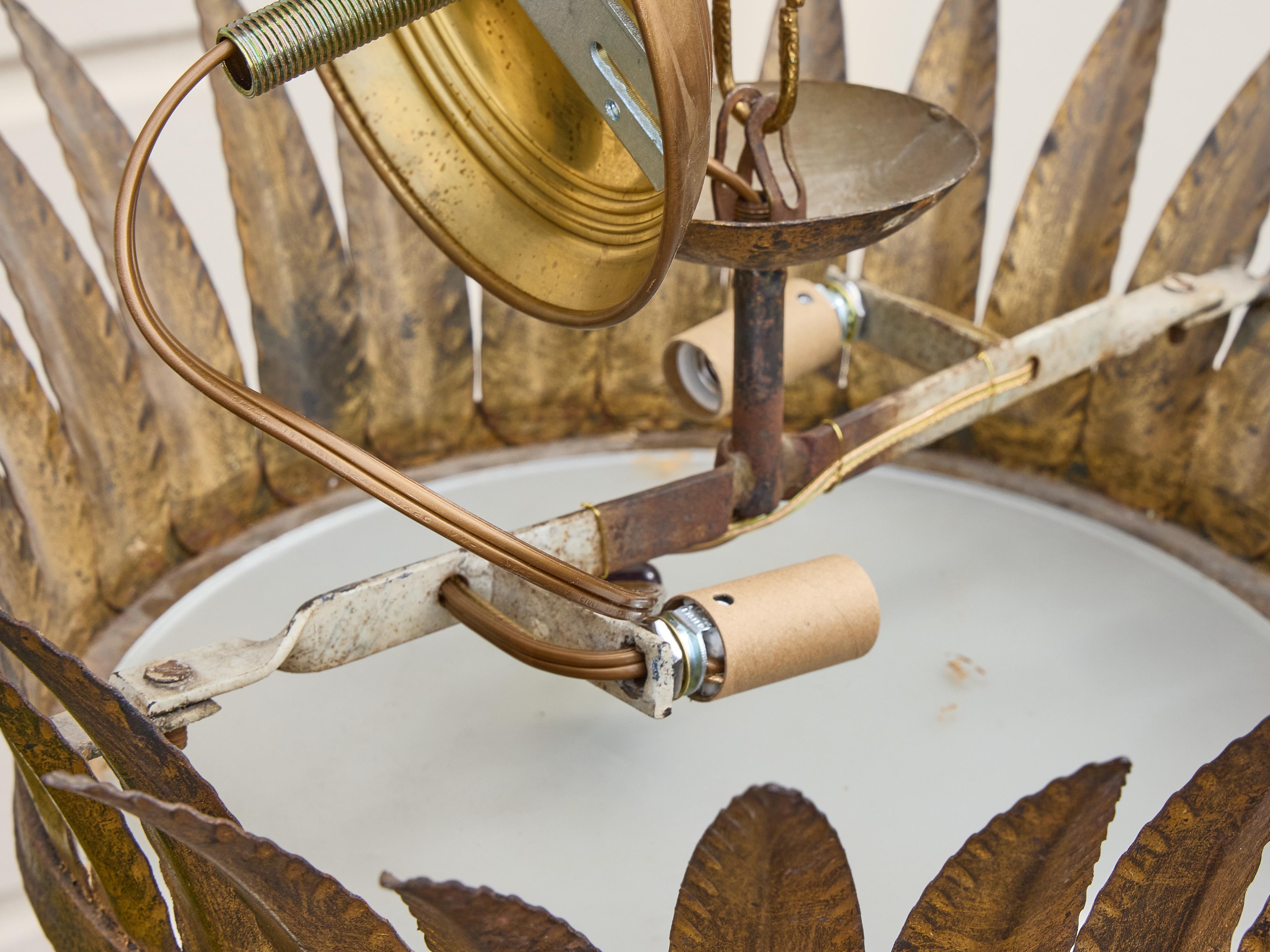 Lampadario spagnolo di metà secolo in metallo dorato con dettagli a forma di foglia e diffusore in vetro smerigliato. Questa plafoniera scultorea, dalla forma simile a una corona, è caratterizzata da un'espressiva serie di foglie di metallo svasate,