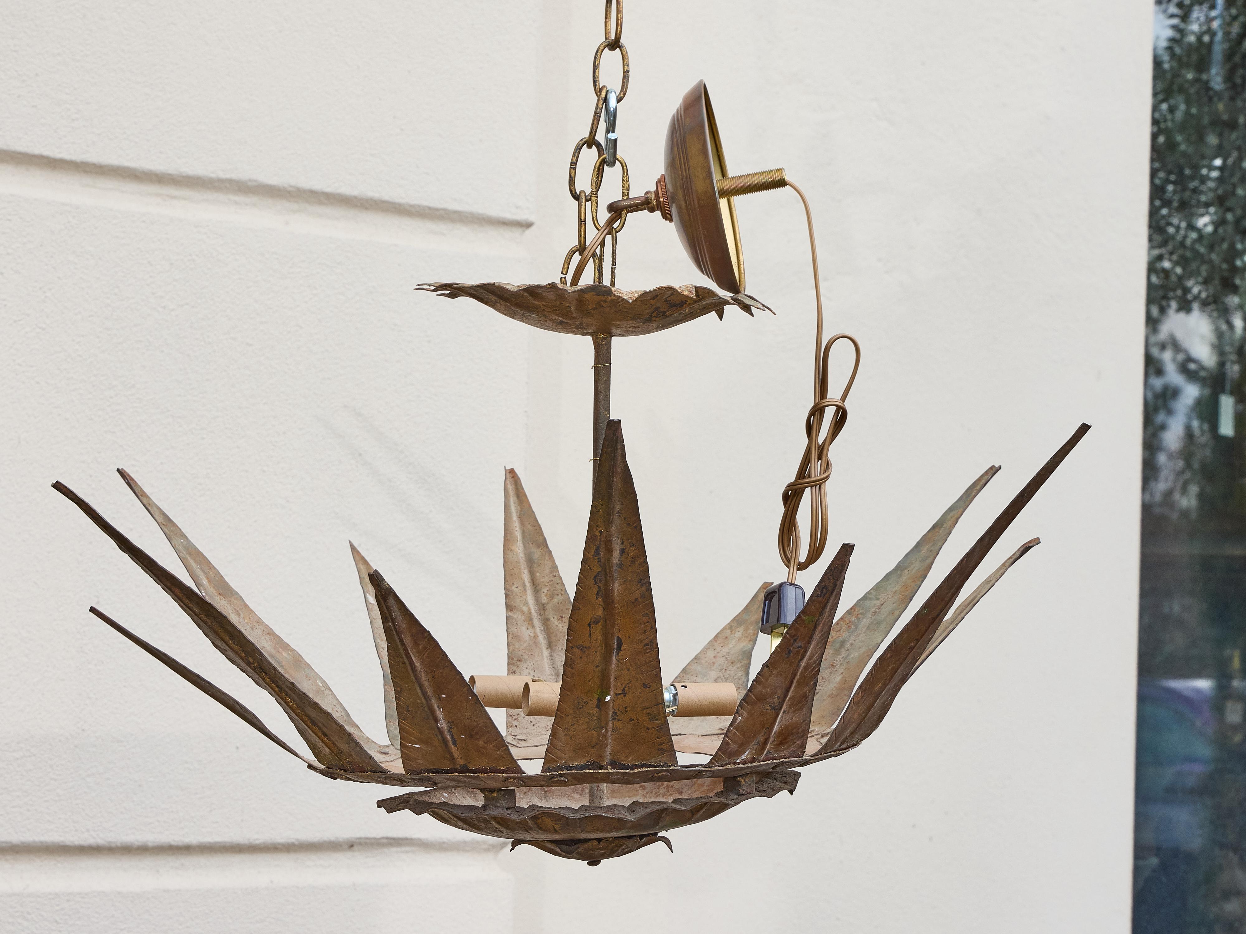 A dramatic midcentury Spanish gilt metal chandelier with a bold sunburst crown form and four interior lights. Hand-forged from textured metal and finished in a warm, timeworn gilt patina, the design features elongated rays radiating from a layered