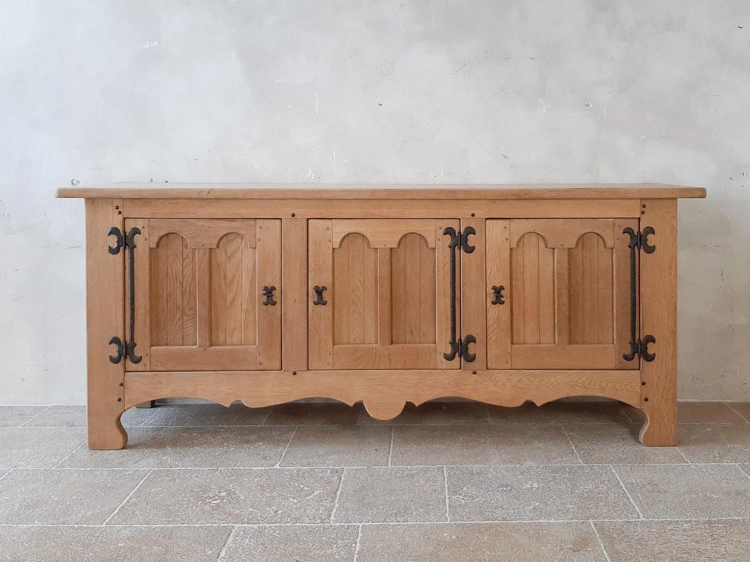 Midcentury Spanish oak credenza. Stunning colonial, brutalist style solid oak sideboard. With three door with double arched panels. Large wrought iron hinges and rivets. With carved detail at the base along the front and sides. Behind the three