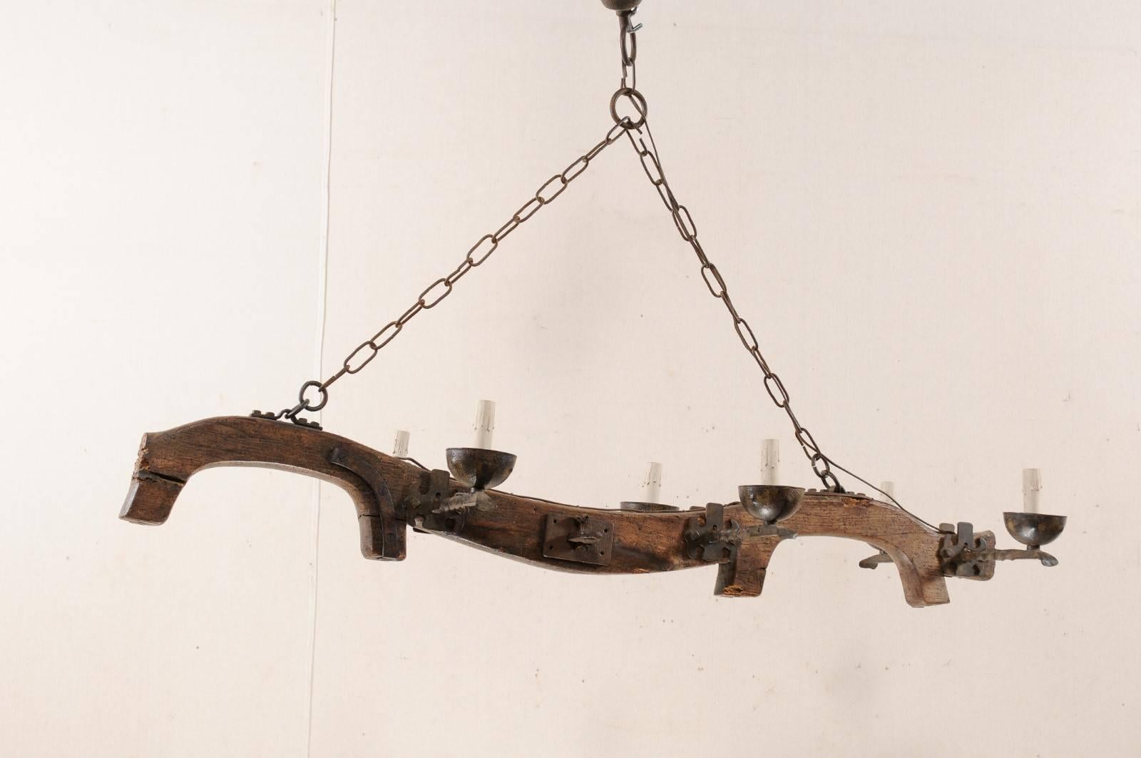 This midcentury Spanish ox yoke has been re-purposed and given a new life in this custom six-light chandelier. The wooden body of this chandelier is the yoke, which is a wooden beam typically used between a pair of oxen (or other animals) to