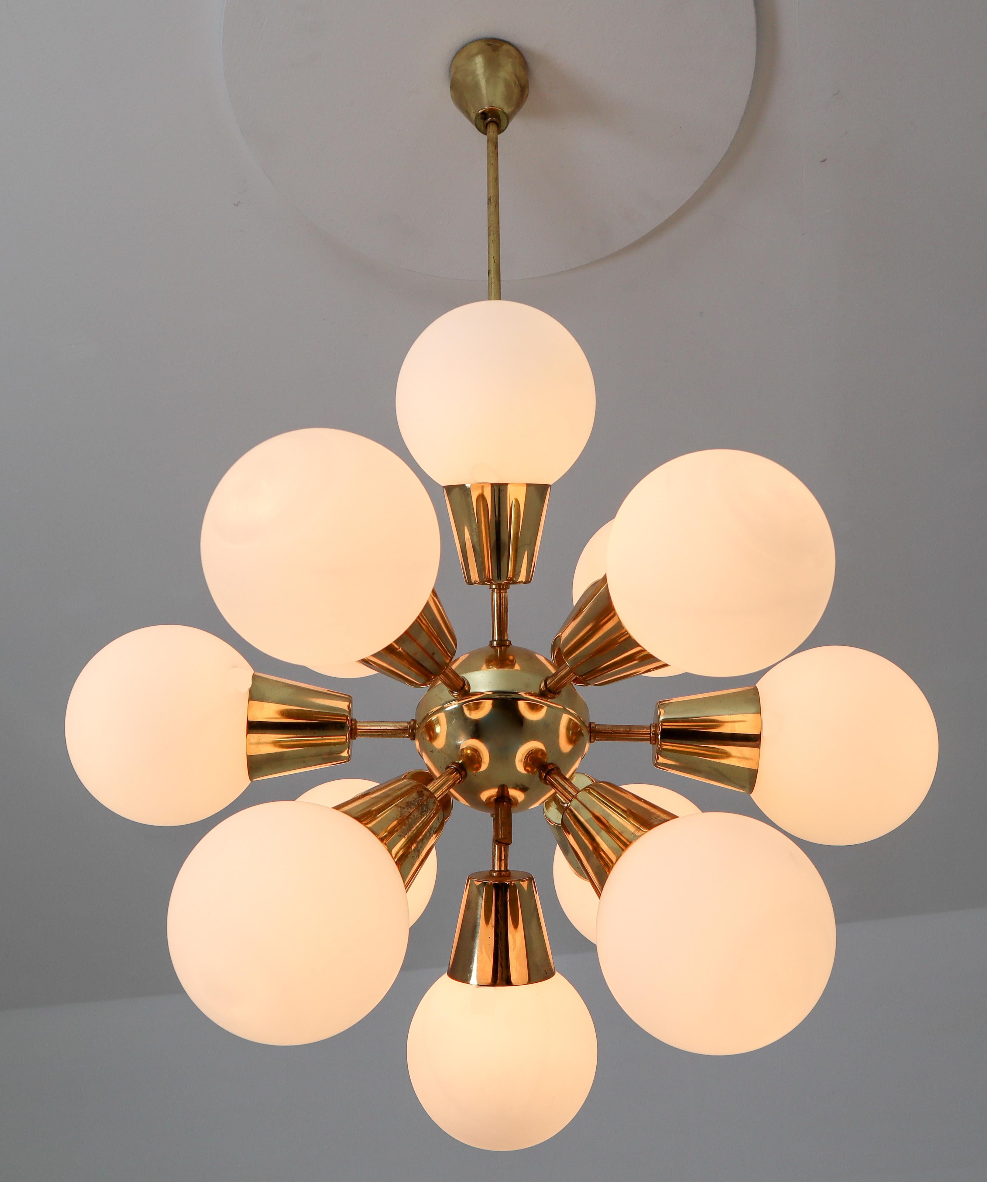 Sputnik chandelier with brass fixture and opaline spheres. These chandeliers with brass frame consist of twelve lights. The diffuse light it spreads is very atmospheric. Completed with the opaline glass and brass details, these chandeliers will