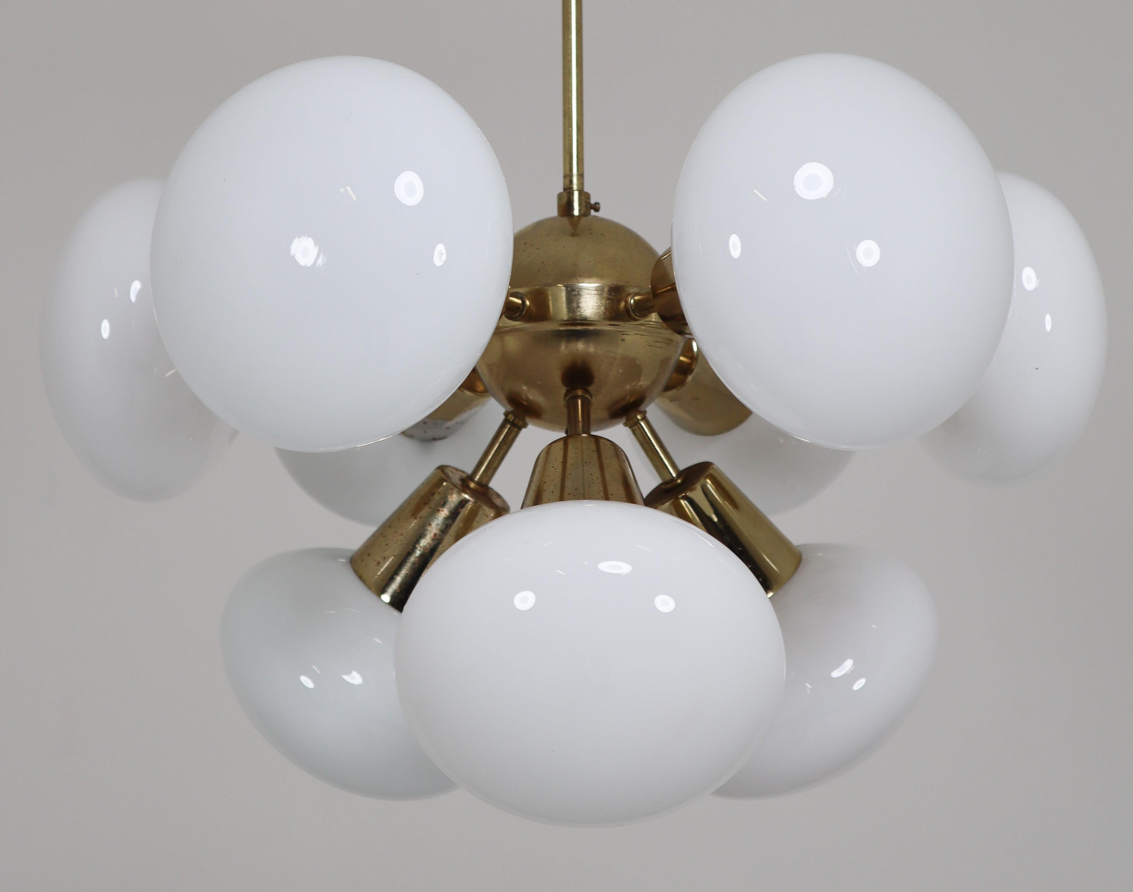 Sputnik chandeliers with brass fixture and opaline spheres. These chandeliers with brass frame consist of twelve lights. The diffuse light it spreads is very atmospheric. Completed with the opaline glass and brass details, these chandeliers will