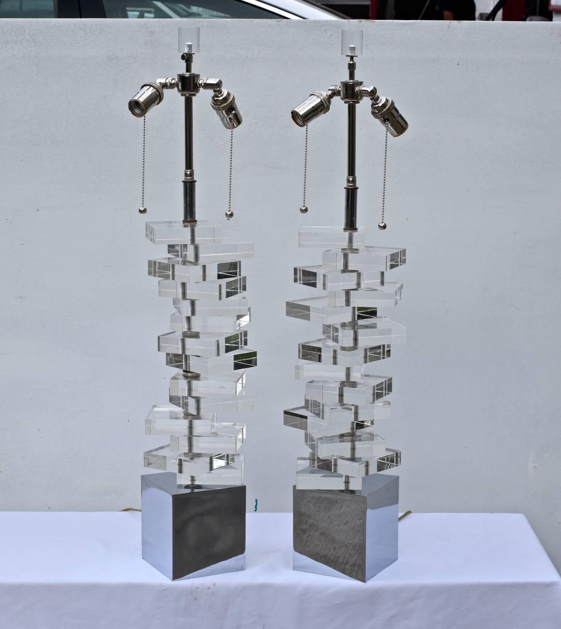 A stunning and unique pair of stacked Lucite lamps having tall and striking chrome bases and nickel double socket clusters up top. The early 1970s, midcentury lights are very clean throughout and will make a dramatic decorative statement wherever