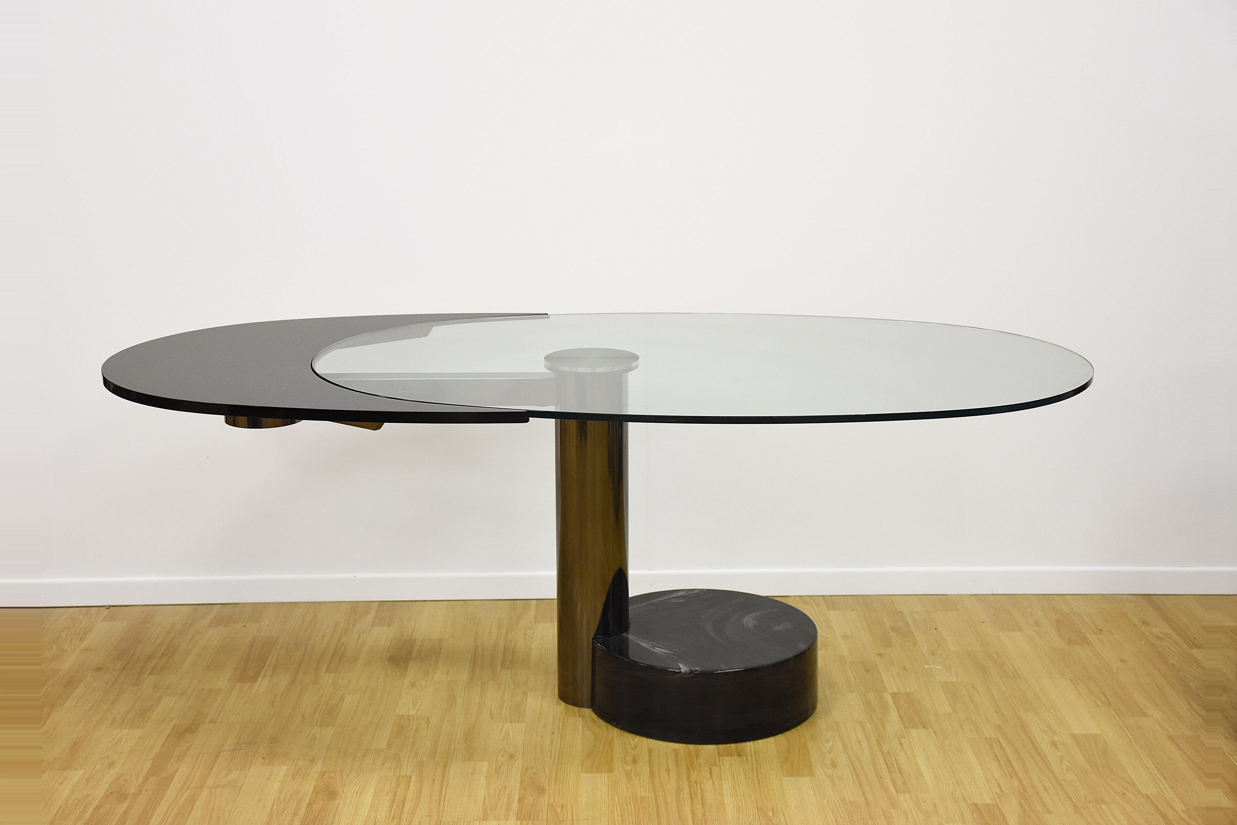 Amazing midcentury steel and glass oval revolving dining table from the 1960s, attributed to Pierre Cardin.

This incredible sculptural dining table rotates in two positions, from oval 100 x 160 cm. Once extended, the black section rises up to the