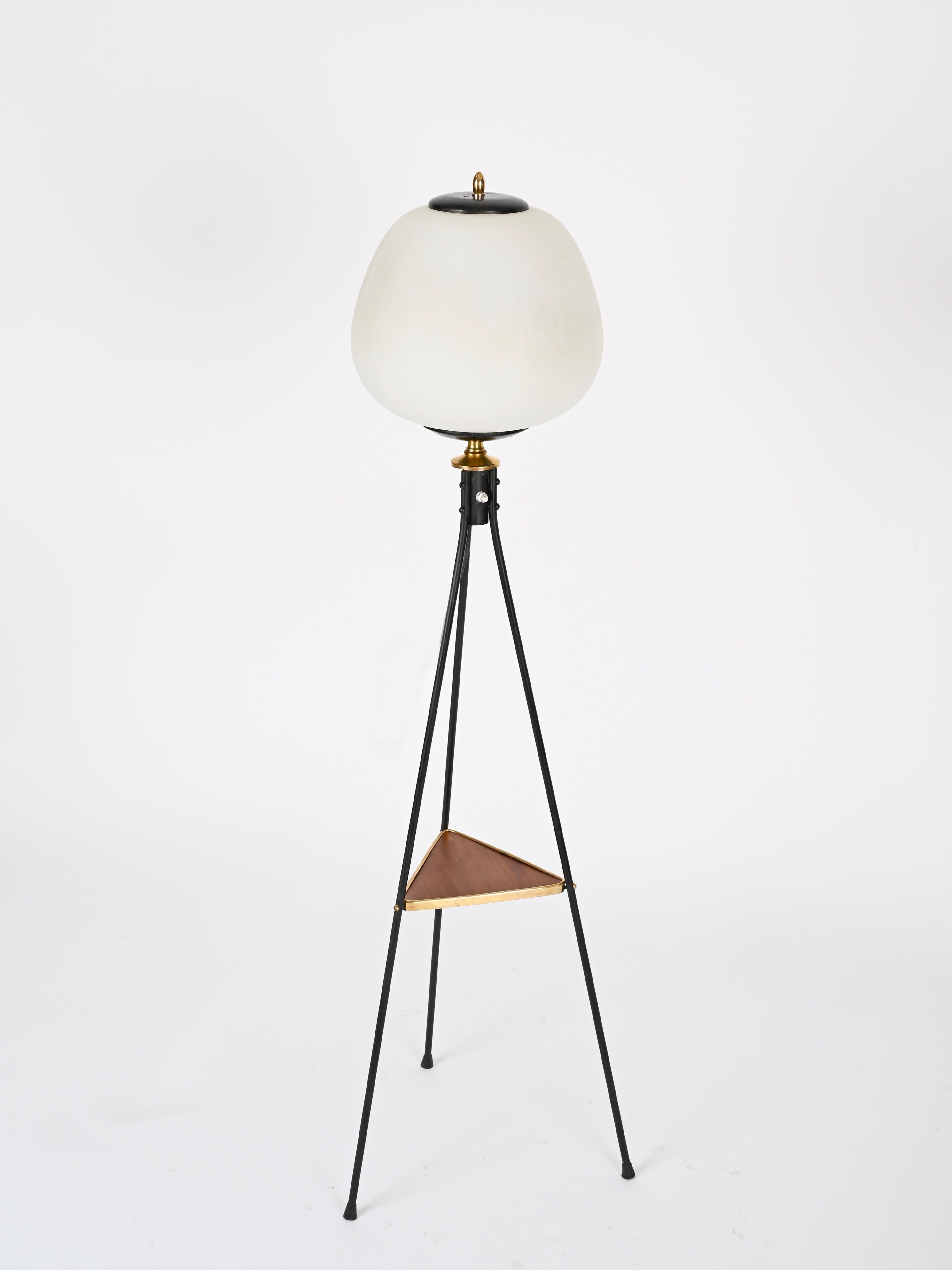 Excepcional lámpara de pie de mediados de siglo, de metal esmaltado negro, latón y madera de teca, completada con un difusor redondeado de cristal opalino. Esta elegante lámpara fue diseñada por Stilnovo y producida en Italia durante la década de