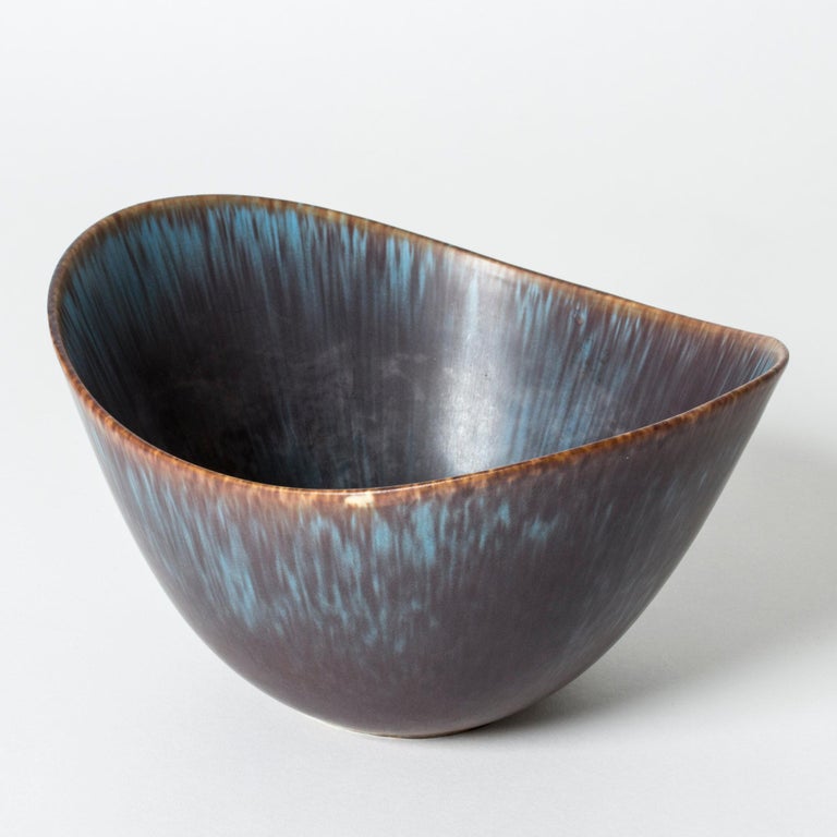Beautiful stoneware bowl by Gunnar Nylund, in an oval boat shape with an undulating edge. Large size. Purple and blue glaze with nuances of brown.

Gunnar Nylund was one of the most influential ceramicists and designers of the Swedish mid-century