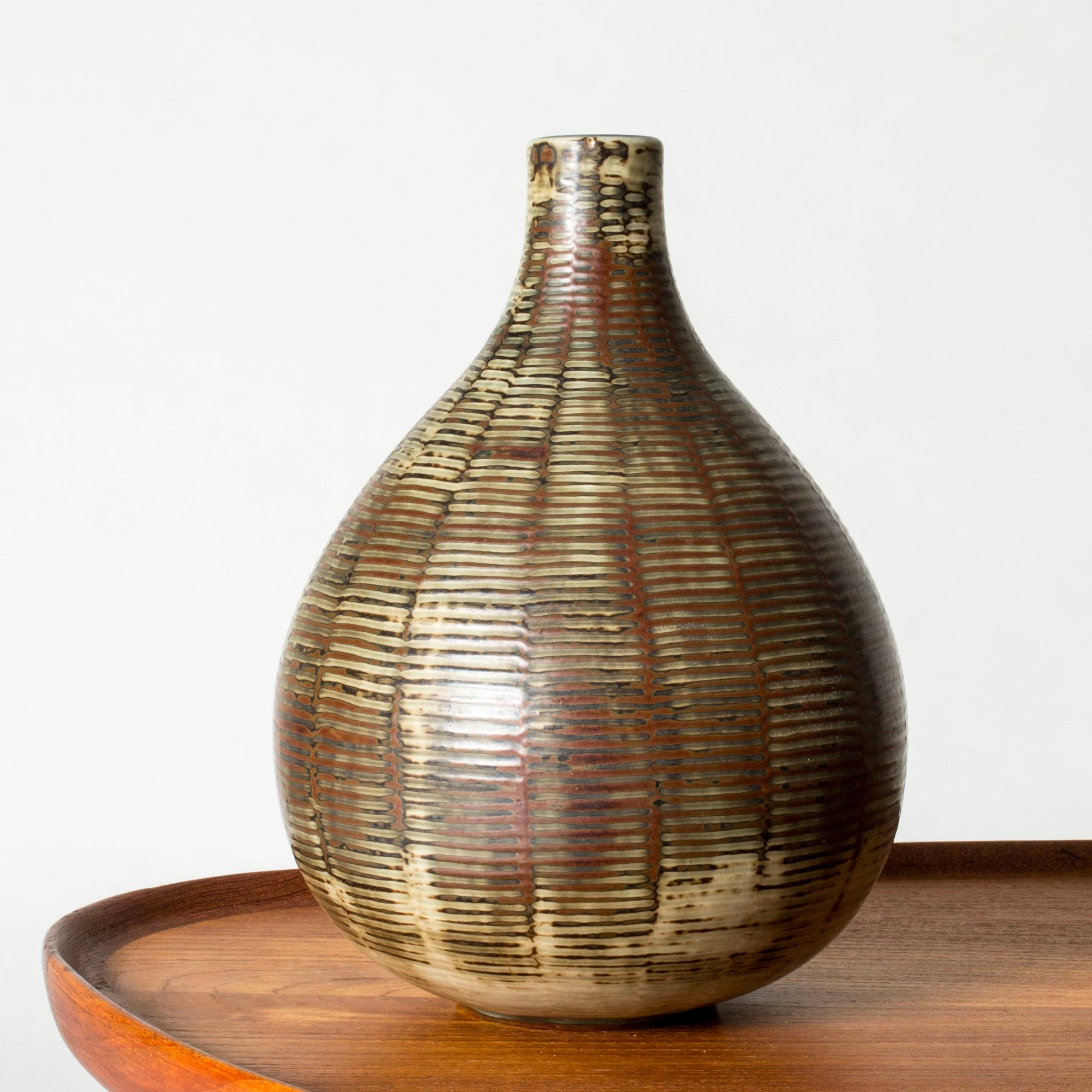 Striking stoneware vase by Axel Salto, in a smooth bulbous form. Graphic pattern of stripes over the body, rustic expression with glaze in nuances of brown and beige.