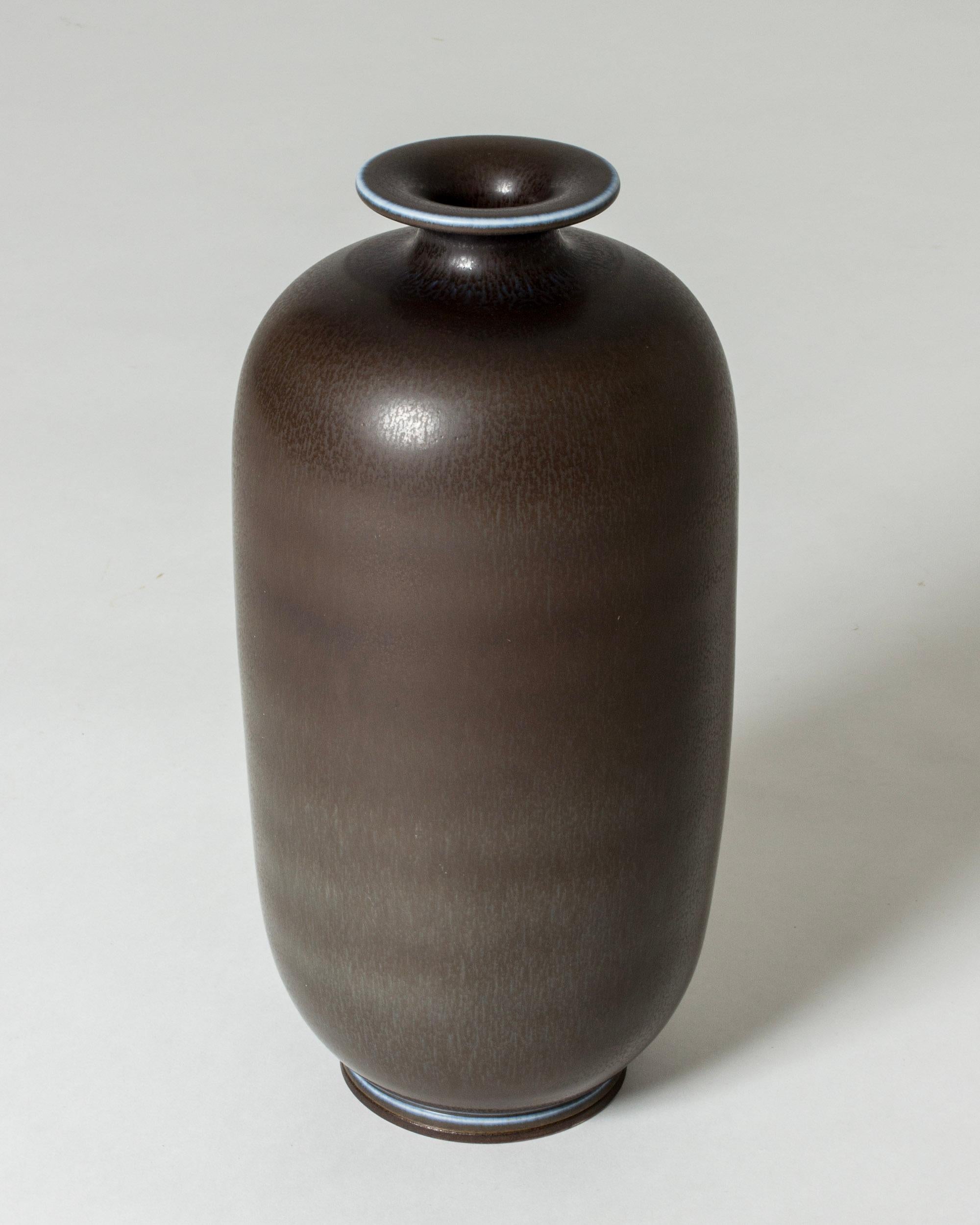 Elegant stoneware vase by Berndt Friberg in a tall, stately form. Brown hare’s fur glaze with blue around the rim and base.

Berndt Friberg was a Swedish ceramicist, renowned for his stoneware vases and vessels for Gustavsberg. His pure, composed
