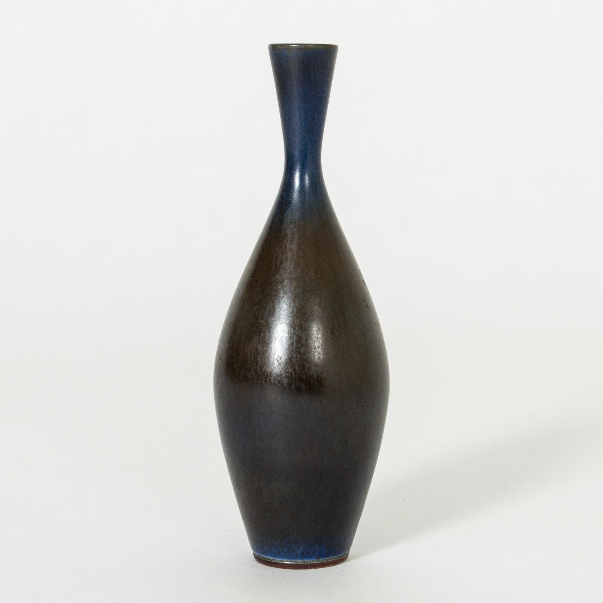 Elegant, small stoneware vase by Berndt Friberg, in a smooth form with dark blue hare’s fur glaze, lighter around the neck. Somewhat glossy finish.

Berndt Friberg was a Swedish ceramicist, renowned for his stoneware vases and vessels for