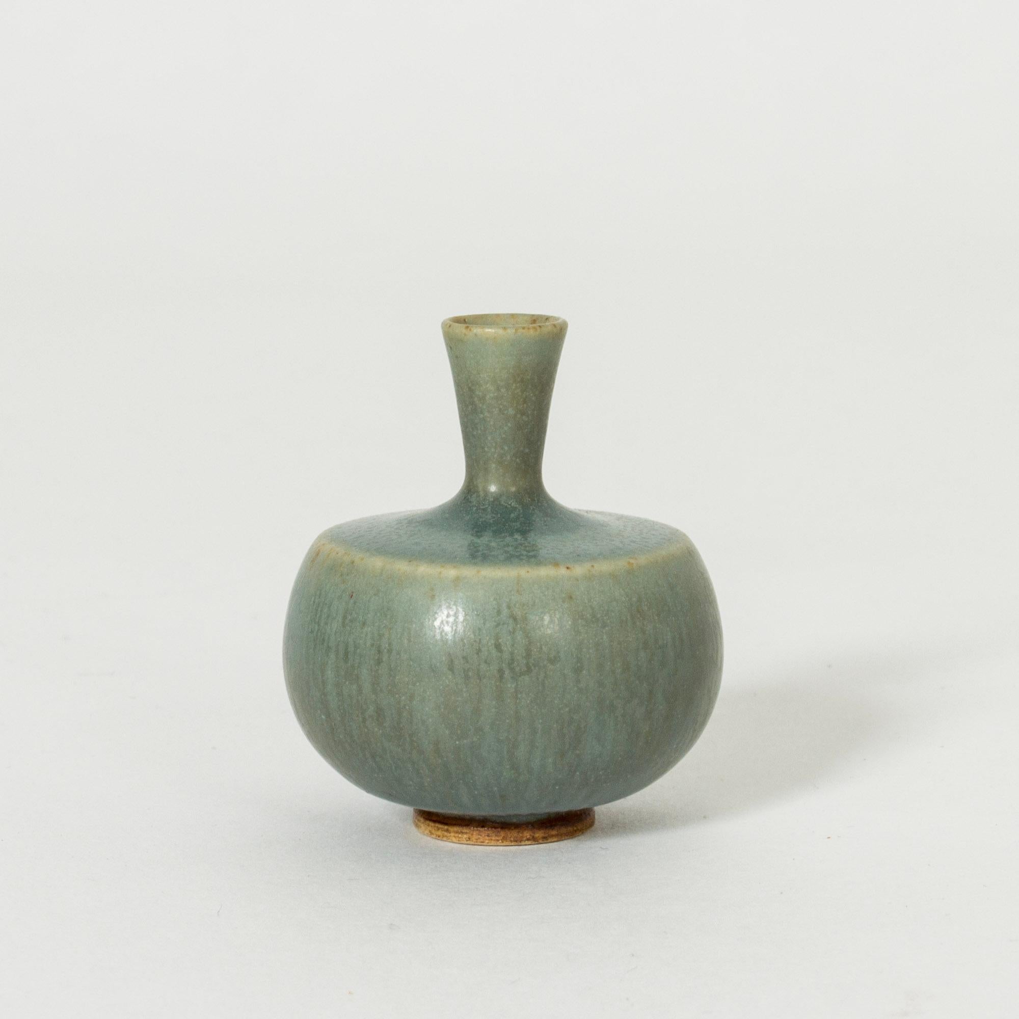 Lovely tiny stoneware vase by Berndt Friberg, in a compact form with celadon green hare’s fur glaze.

Berndt Friberg was a Swedish ceramicist, renowned for his stoneware vases and vessels for Gustavsberg. His pure, composed designs with satiny,
