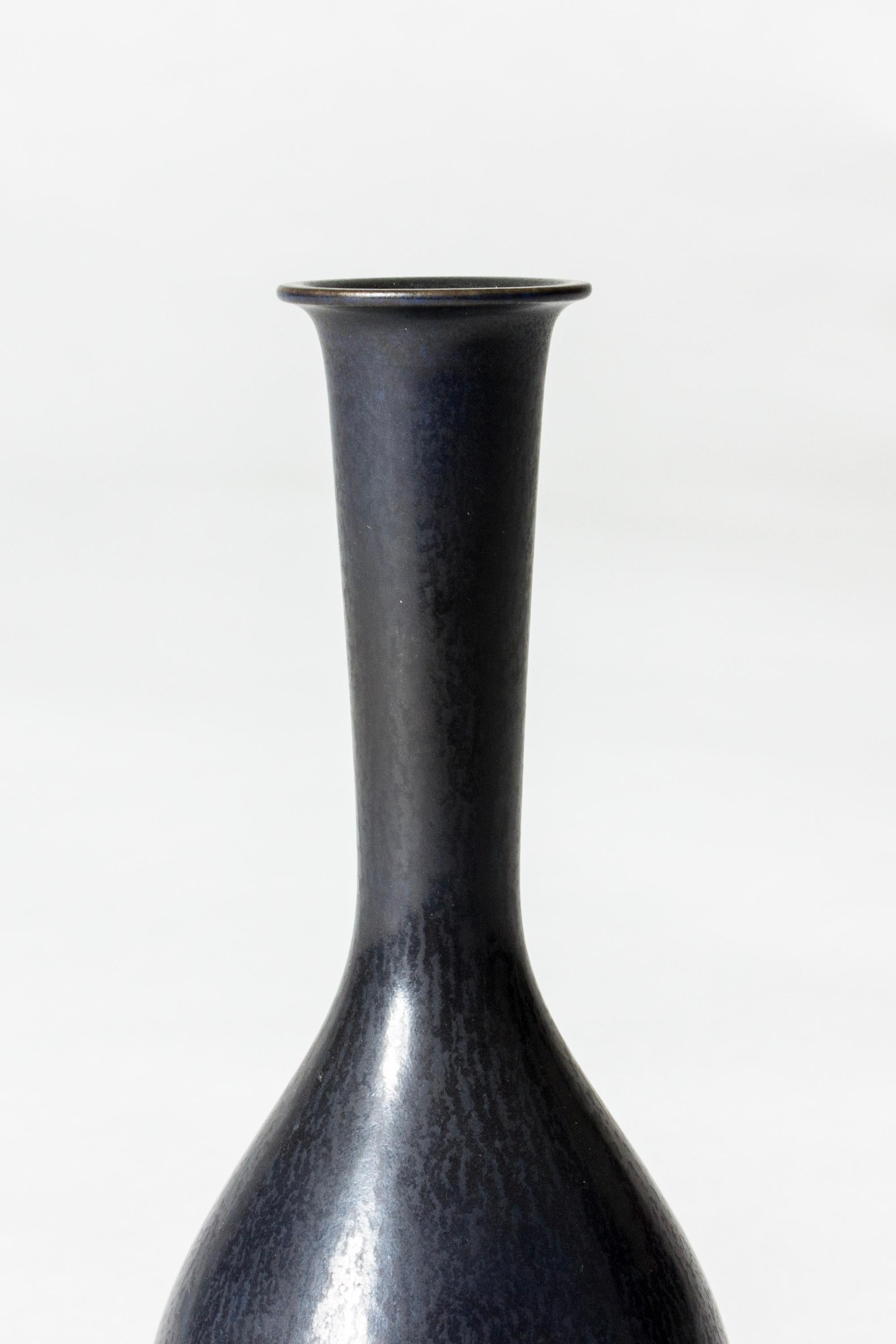 Small stoneware vase by Berndt Friberg, in a slender onion form with a long neck and flattened rim. Velvety midnight blue hare’s fur glaze.

Berndt Friberg was a Swedish ceramicist, renowned for his stoneware vases and vessels for Gustavsberg. His