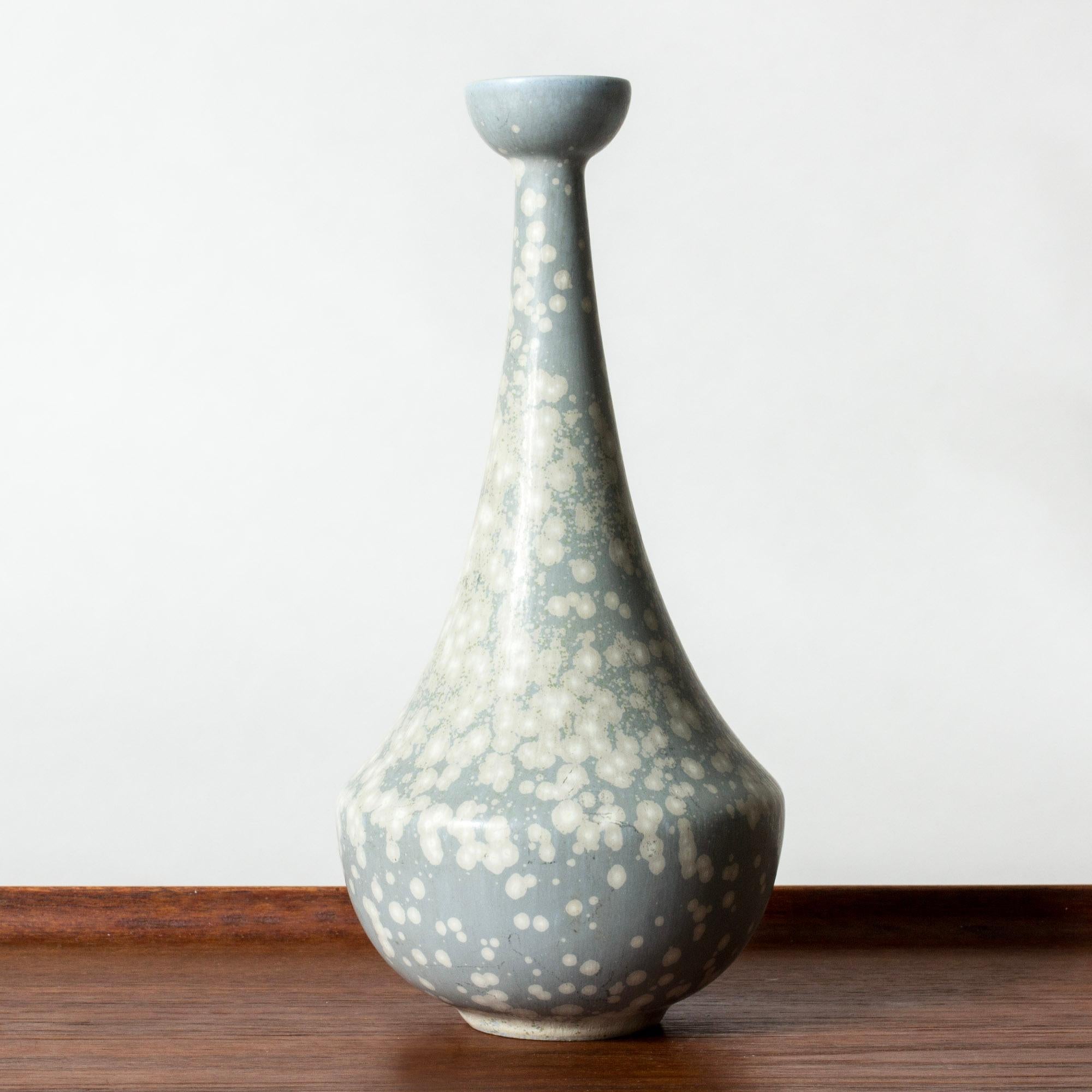 Hübsche Vase aus Steinzeug von Gunnar Nylund in einer geschwungenen, sich verjüngenden Form. Blassblau glasiert mit weißem 