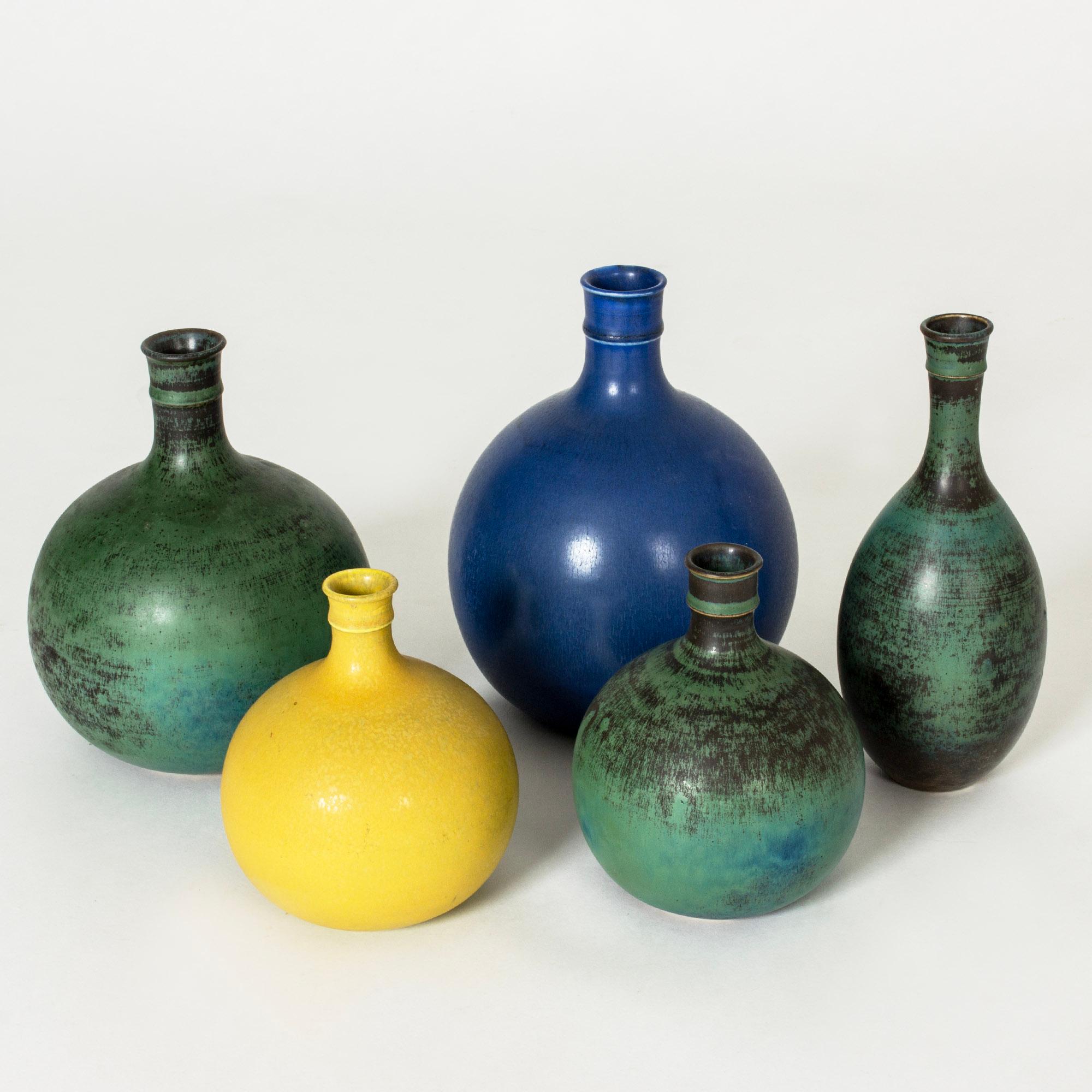 Set of five stoneware vases by Stig Lindberg, from the series “Drejargods”. Bulbous forms with striking colors. One blue and one yellow, the others green with hues of blue and streaks of dark brown.

Height 13.5-20 cm, Diameter 7.5-15 cm