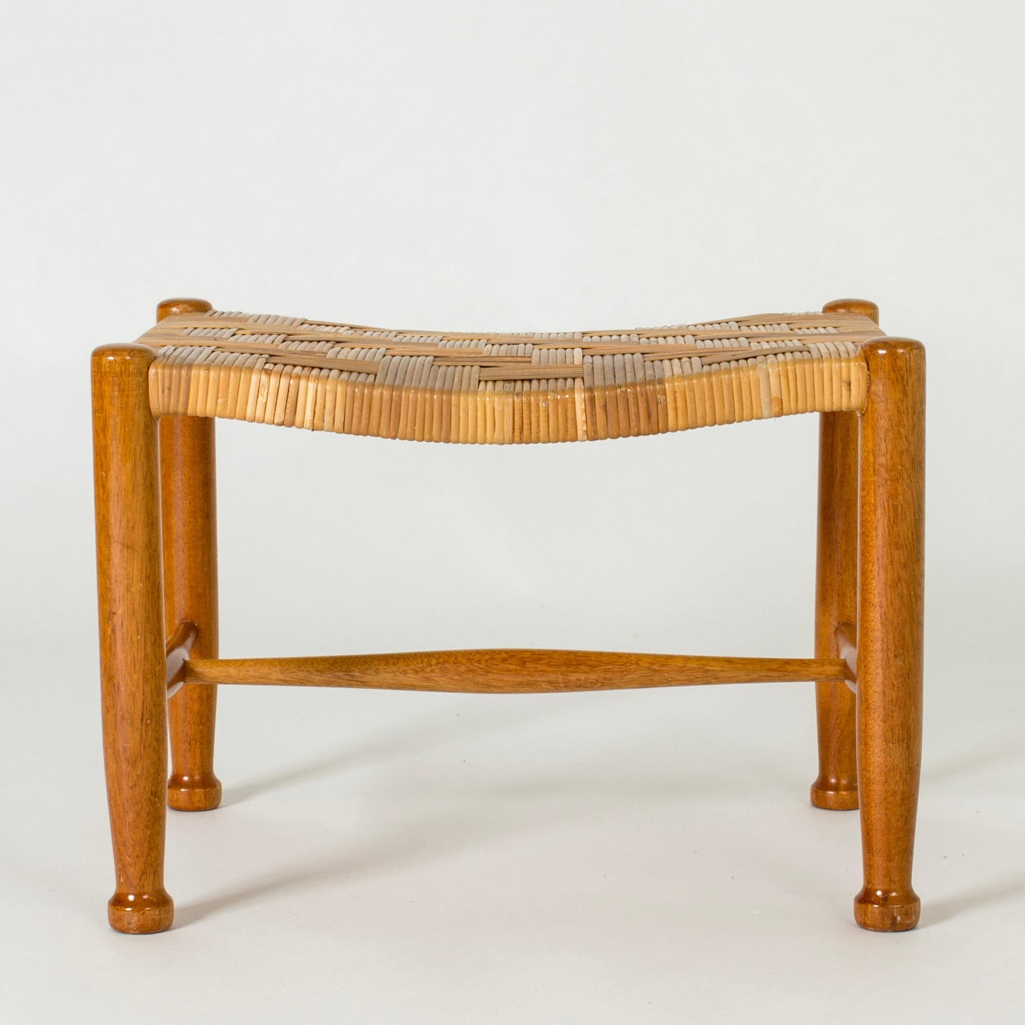 Neat stool by Josef Frank, made from mahogany with elegantly sculpted feet. Rattan seat in a densely wreathed pattern.