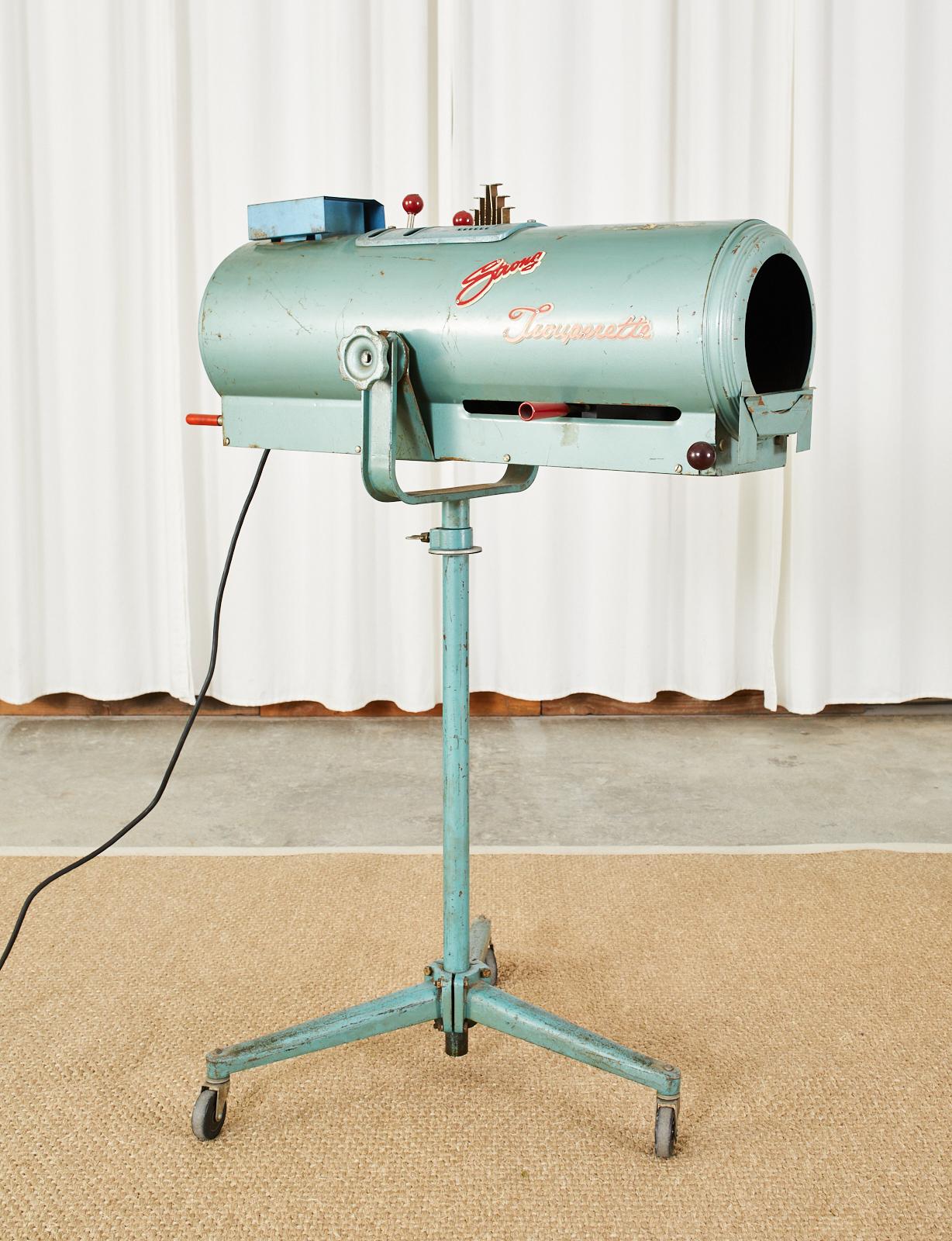 Industrial style Mid-Century Modern strong Trouperette theater stage spotlight mounted on a tripod iron Stand. As found working condition with original teal blue color and vintage patina on the finish. Working filters, zoom controls, and handles to