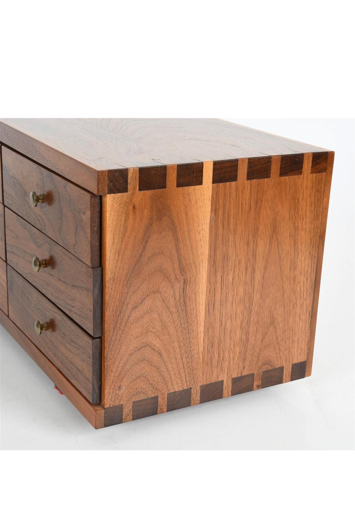 Mid century studio craft small chest of drawers in solid walnut construction with wide detailed joinery. Very high quality construction with brass pulls. Custom made for top of dresser or bookcase. 6 brass knobs 6 individual drawers. Made in the