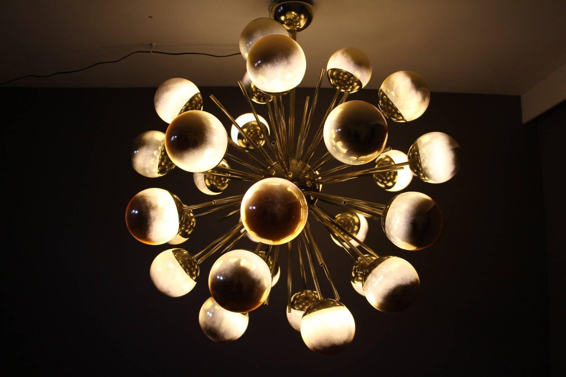 This very chic chandelier features brass rods ending with gold glass globes.
So when the light is switched off, this chandelier is all gold, amazing. And when light is switched on, each globe looks like a kind of planet, and light gets out around