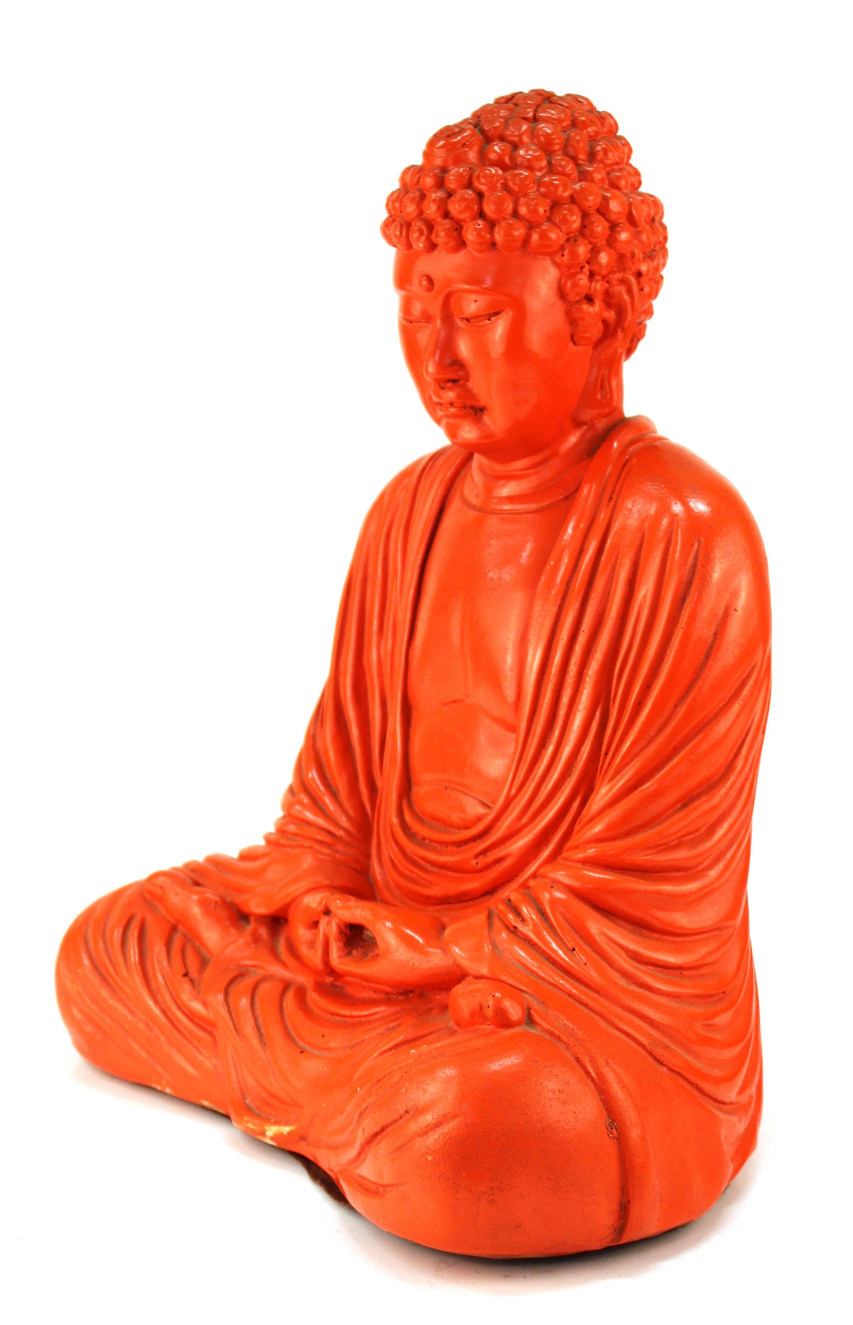 Midcentury style painted plaster seated Buddha figure, painted in orange. The piece is in good vintage condition, with some chips to the paint and plaster.