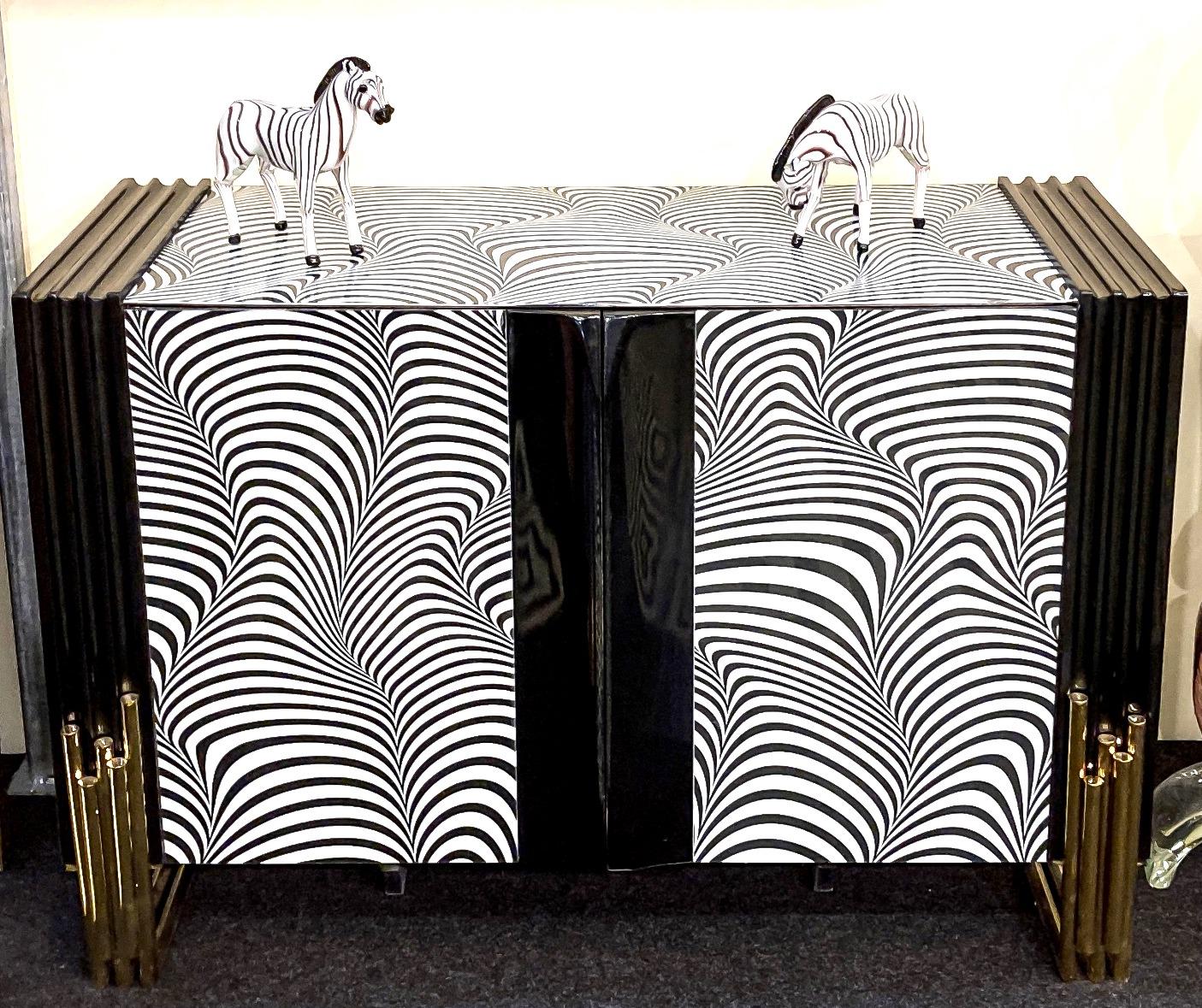 Credenza di grande pregio realizzata a mano da un maestro artigiano. Struttura in ottone con vetro di Murano opalino Zebra bianco e nero tagliato a mano, sollevata su speciali gambe in ottone.
 
