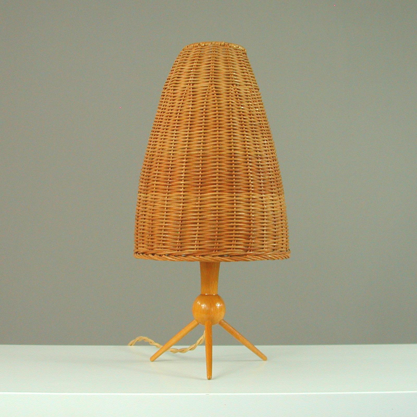This elegant Scandinavian Modern table lamp was designed and manufactured in Sweden in the 1950s. It features a teak tripod base with a rattan conical lampshade and requires a E27 bulb.

An awesome design with period style tapered teak stem and