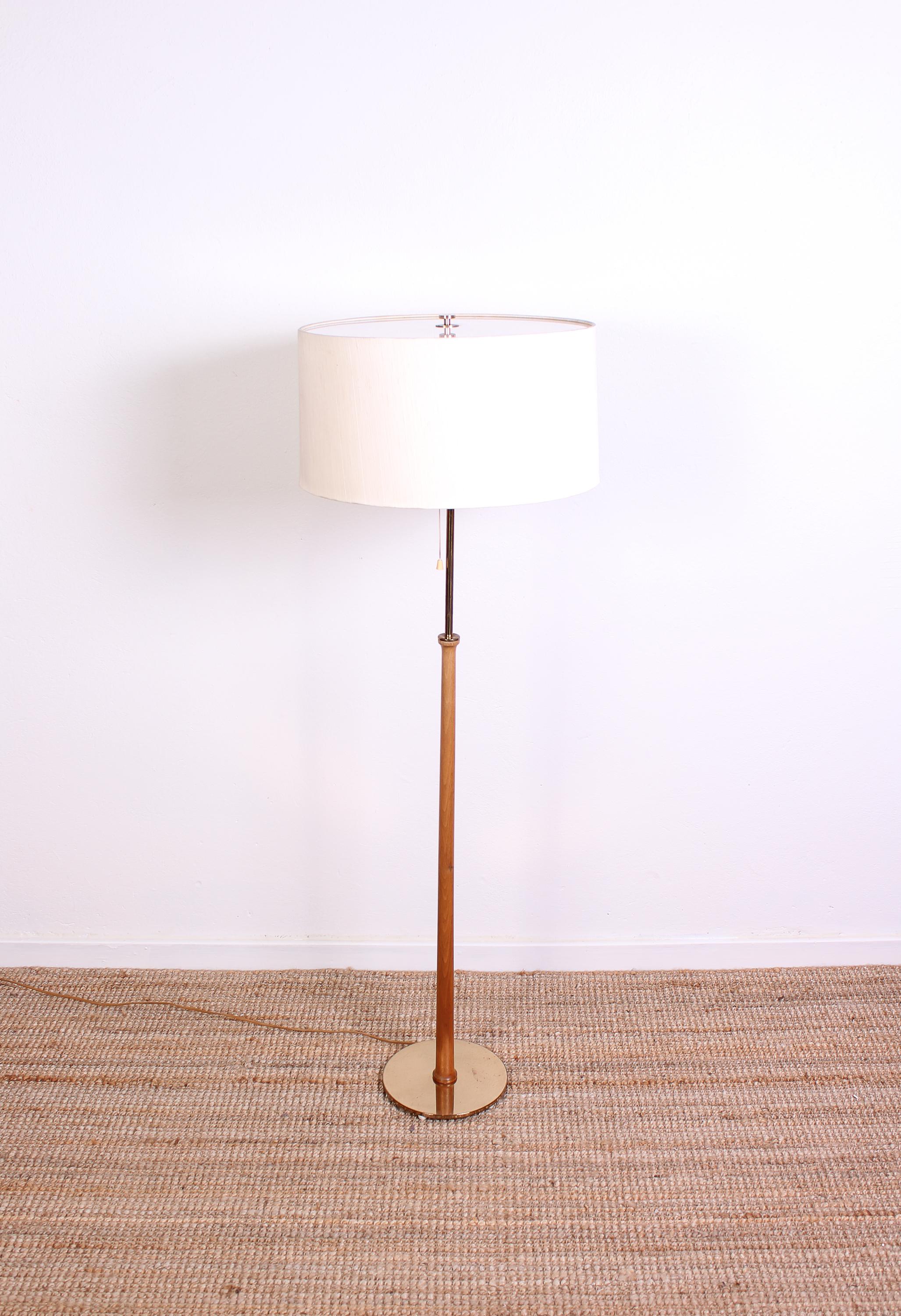 A midcentury floor lamp of high quality by Swedish manufacturer Bergboms. The lamp is made out of brass and teak with its original shade. Good vintage condition with signs of usage consistent with age.