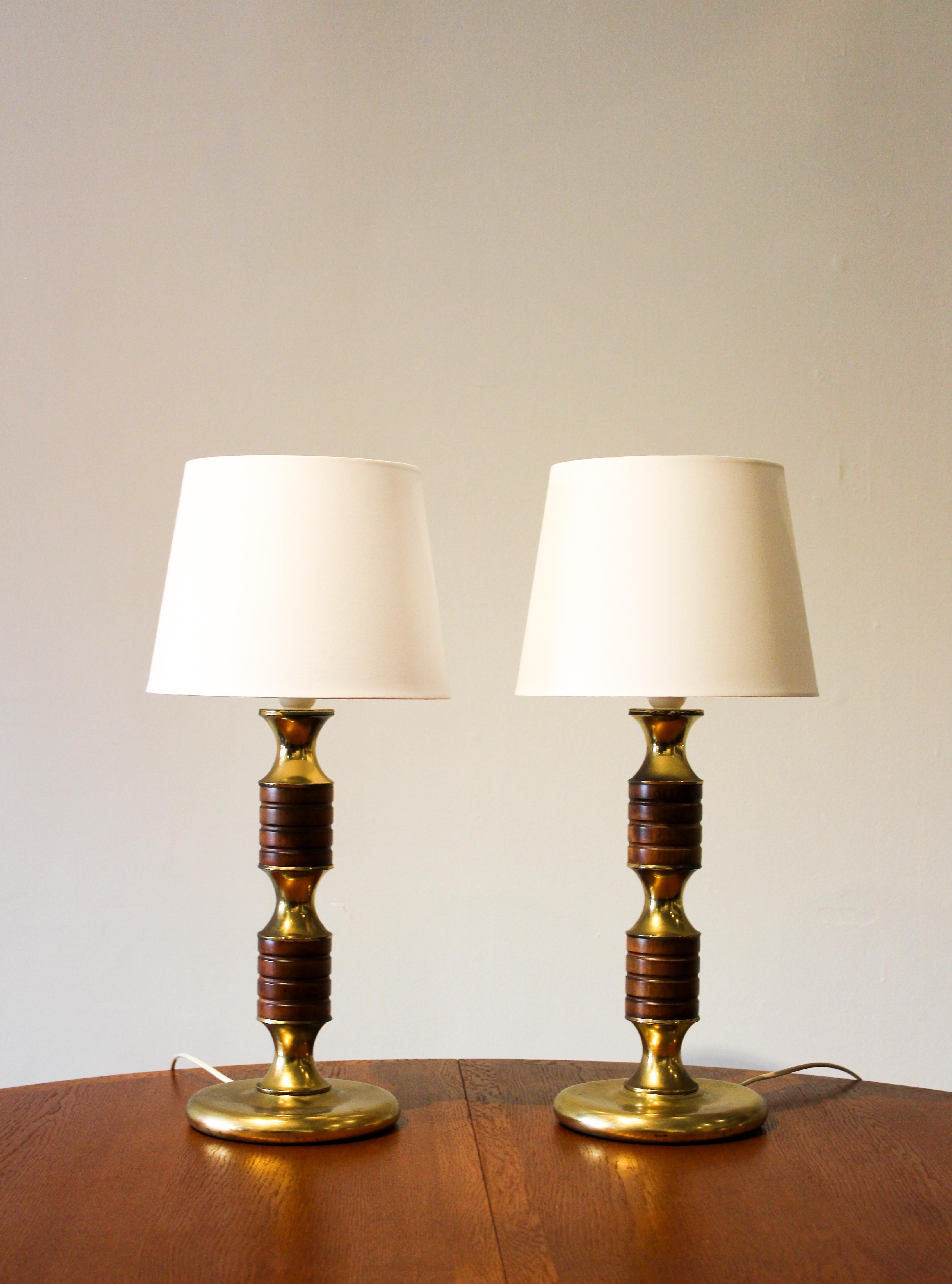A pair of very decorative table lamps made in Sweden during the 1950s. The lamps are made out of brass with teak details. The condition is good with signs of usage and patina consistent with age. Sold as a pair. The shades are newer and not