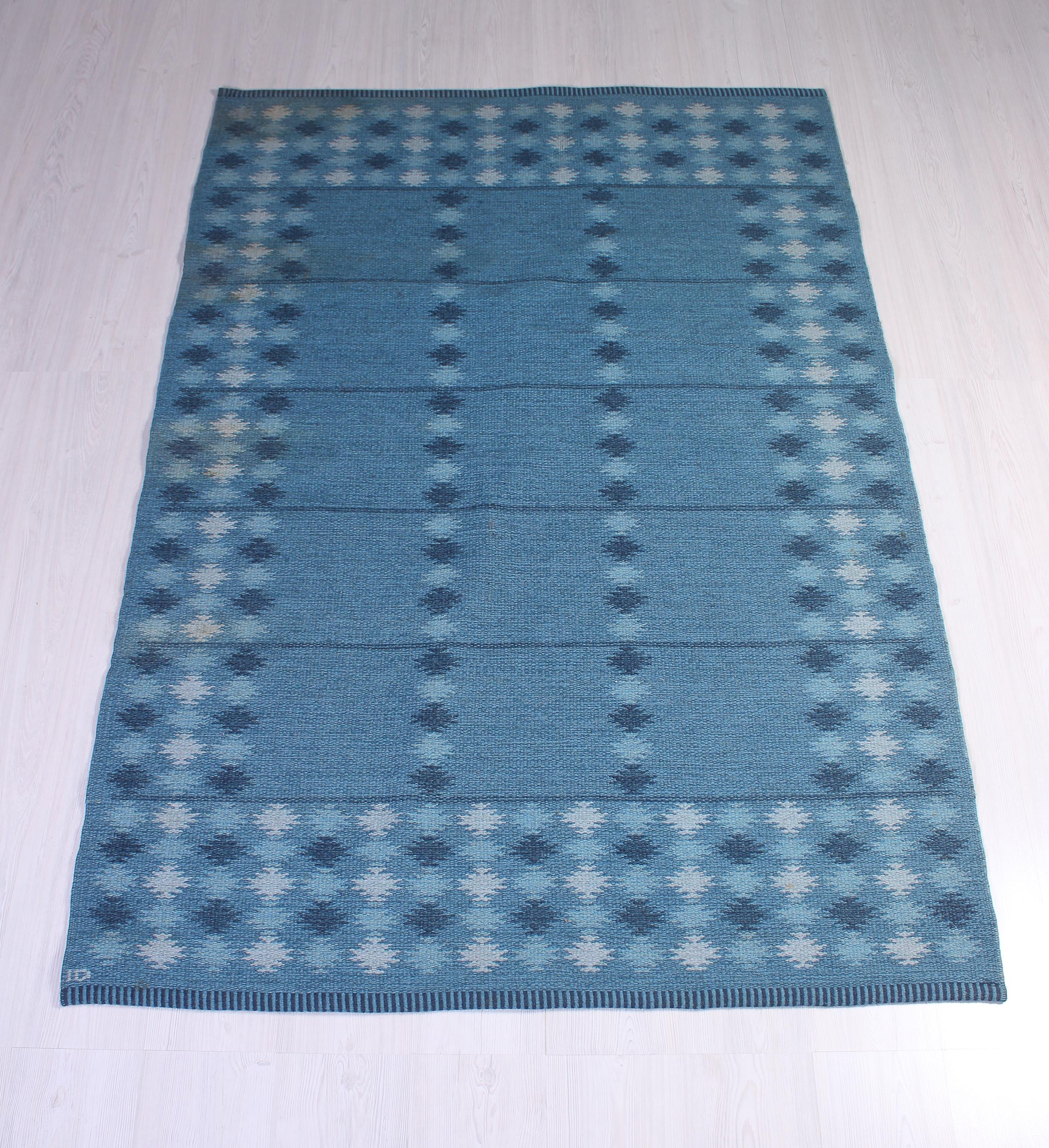 A midcentury Swedish flat-weave carpet by Ingrid Dessau. The carpet has a beautiful blue base with patterns in dark blue, light blue and white. The carpet is in very good vintage condition without any damages. There are some minor signs of usage but