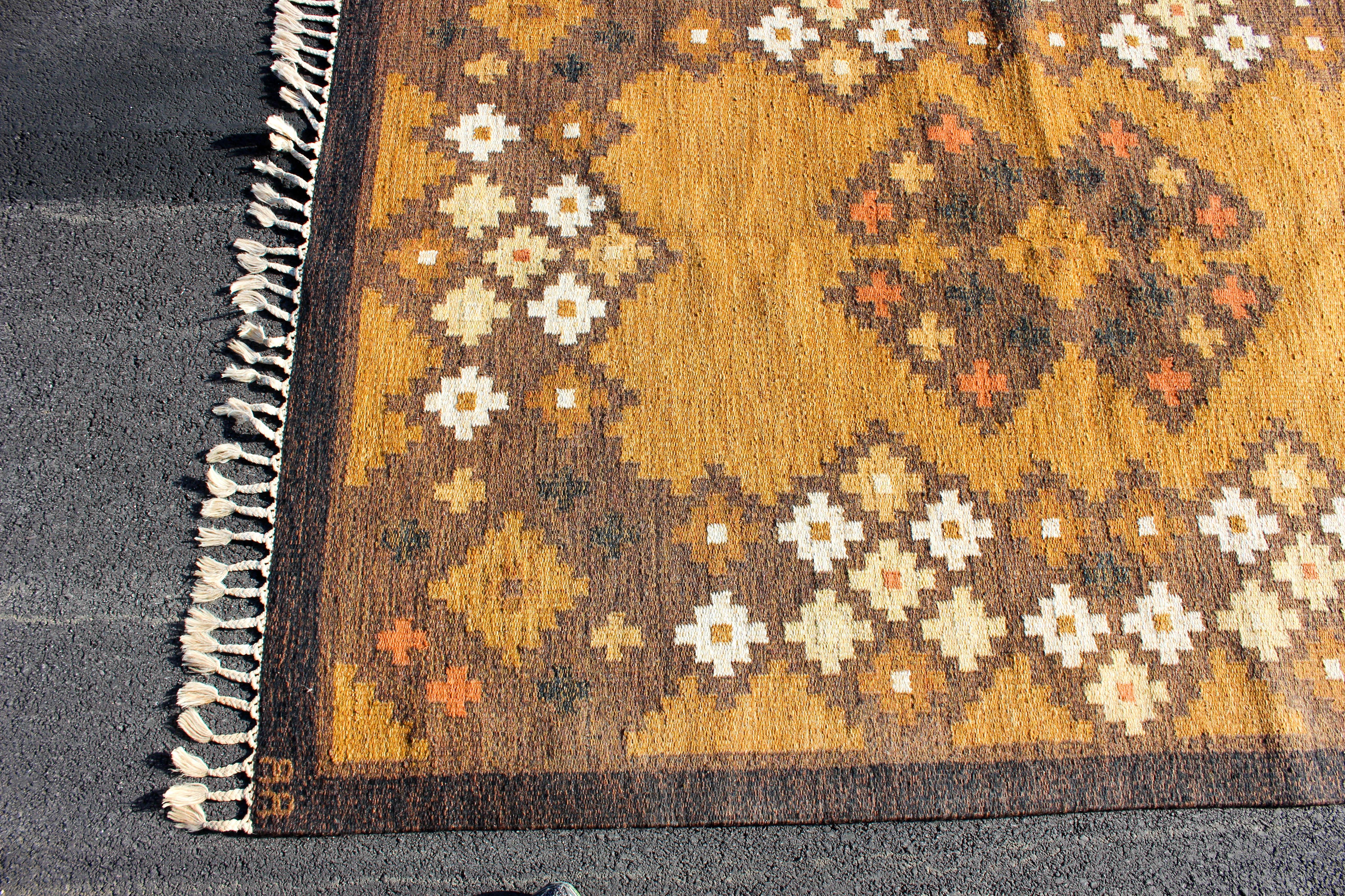 A midcentury Scandinavian carpet (flatware technique) handmade in Sweden during the 1950s. The carpet has a brown base and multicolored geometrical patterns. Very good vintage condition with minor signs of usage.