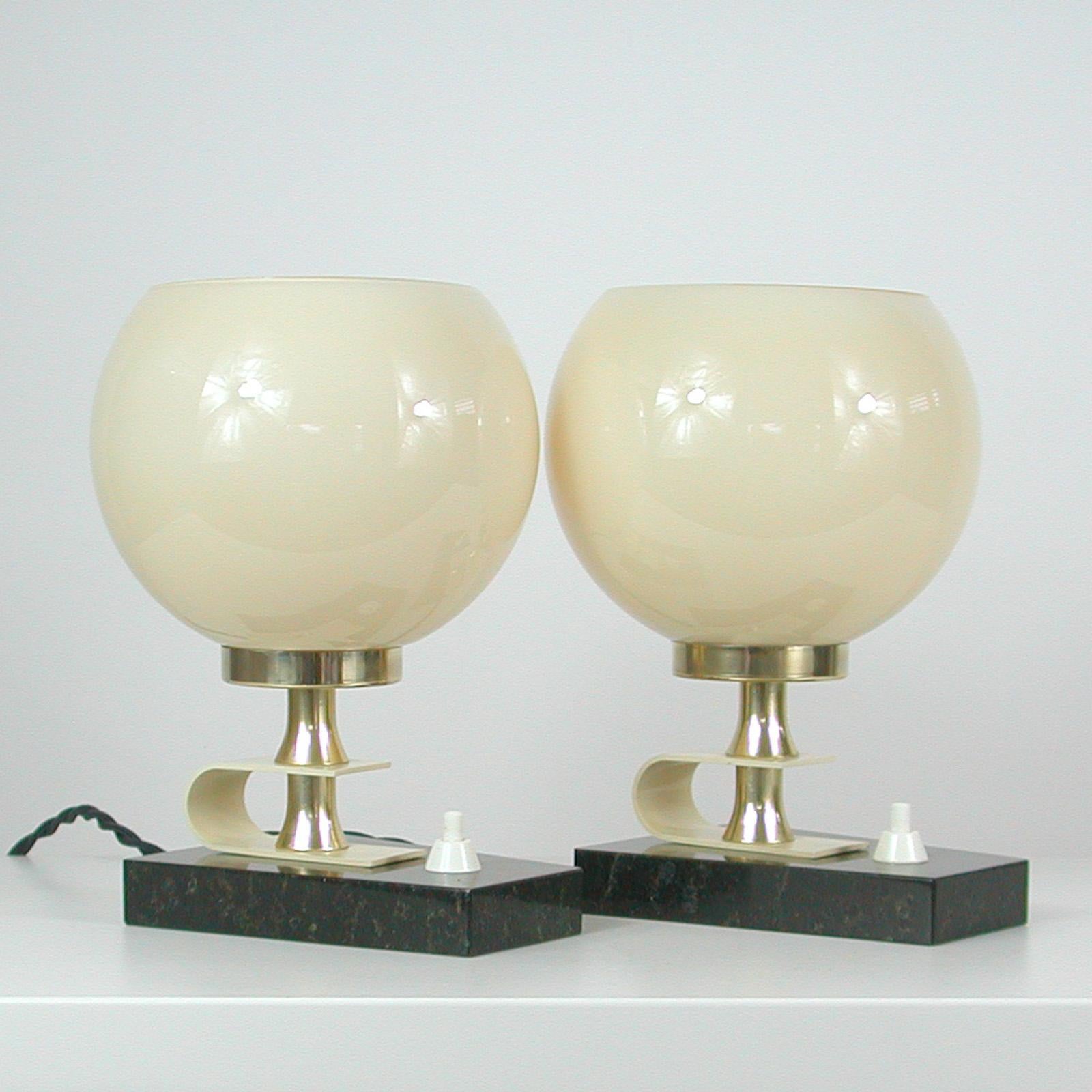 This beautiful modernist set of table or bedside lamps was designed and manufactured in Sweden in the late 1940s to 1950s.

The lights feature black marble bases, ball shaped ivory colored opaline lamp shades and brass hardware. Both have been