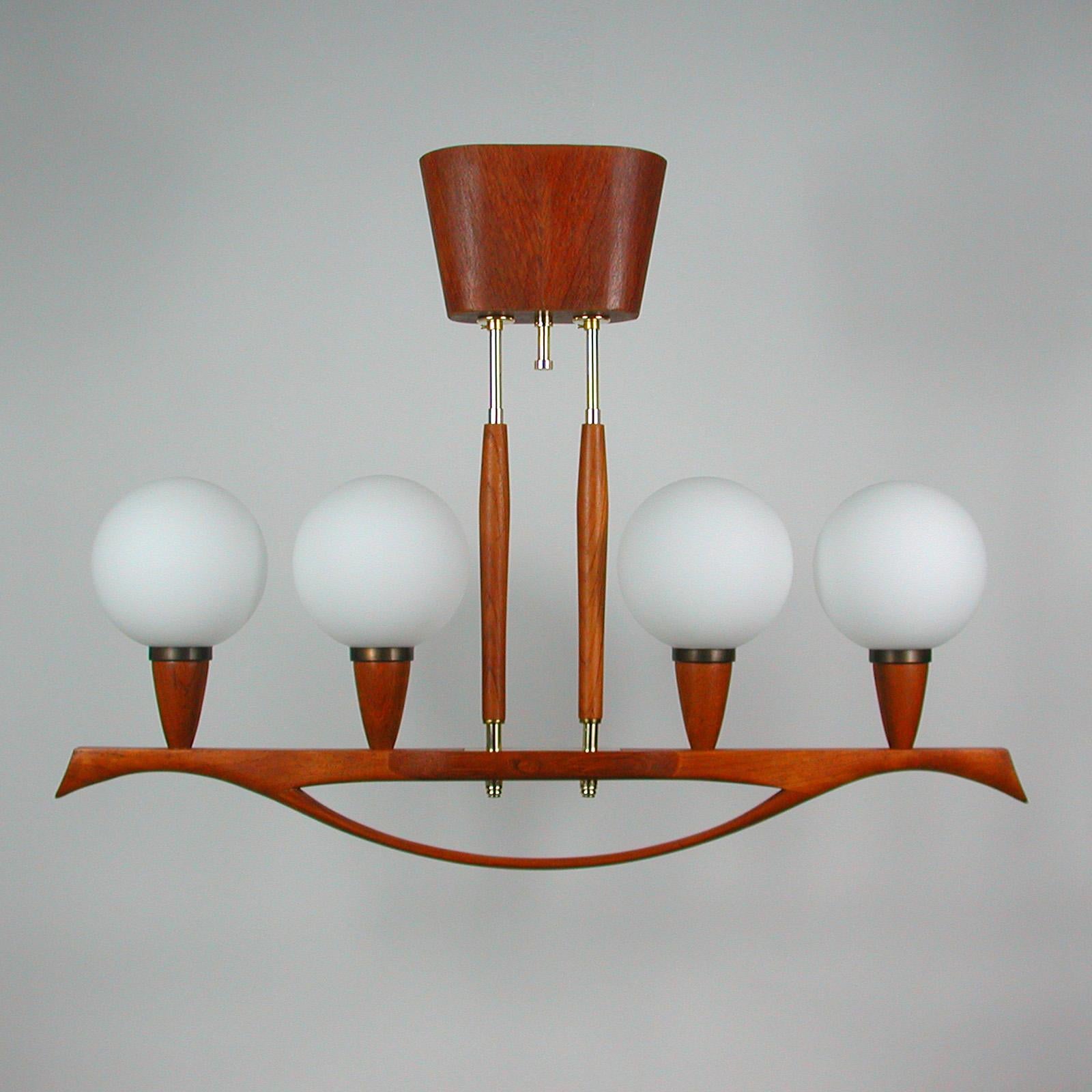 This beautiful vintage four-light chandelier was manufactured in Sweden in the 1960s. It is made of brass and teak and has got 4 satin opal glass lampshades.

Condition is very good and the lamp is in full working order, cleaned and all brass