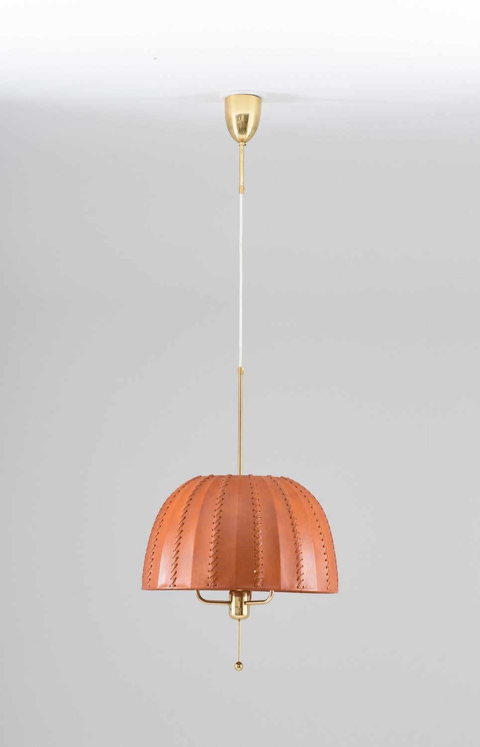 A magnificent and rare pair of pendants in brass and leather by Hans-Agne Jakobsson, Sweden, 1960s.
The lamps feature three-light sources, surrounded by a shade made of brown leather.

Condition: Very good original condition with some small spots