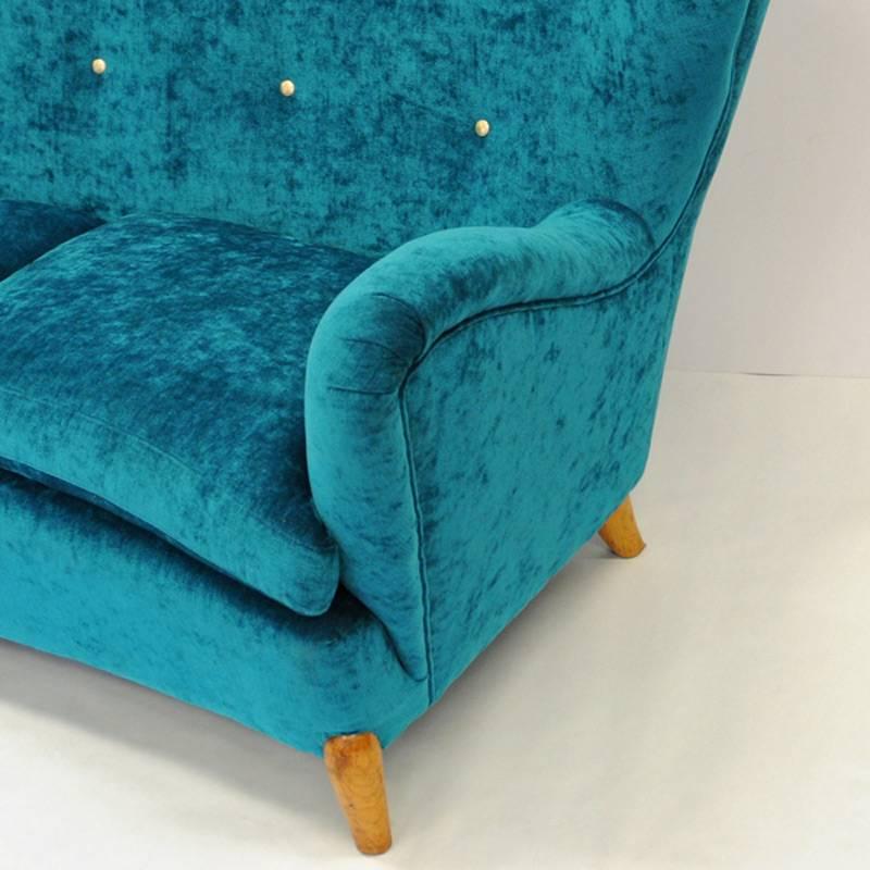 A rare and special one of a kind 1940`s sofa with high comfortable back and soft deep cushions that are removable. New upholstery in blue/green soft plush. Beautiful brass knobs decorations on the back. Wooden legs and stom. Swedish produced sofa of