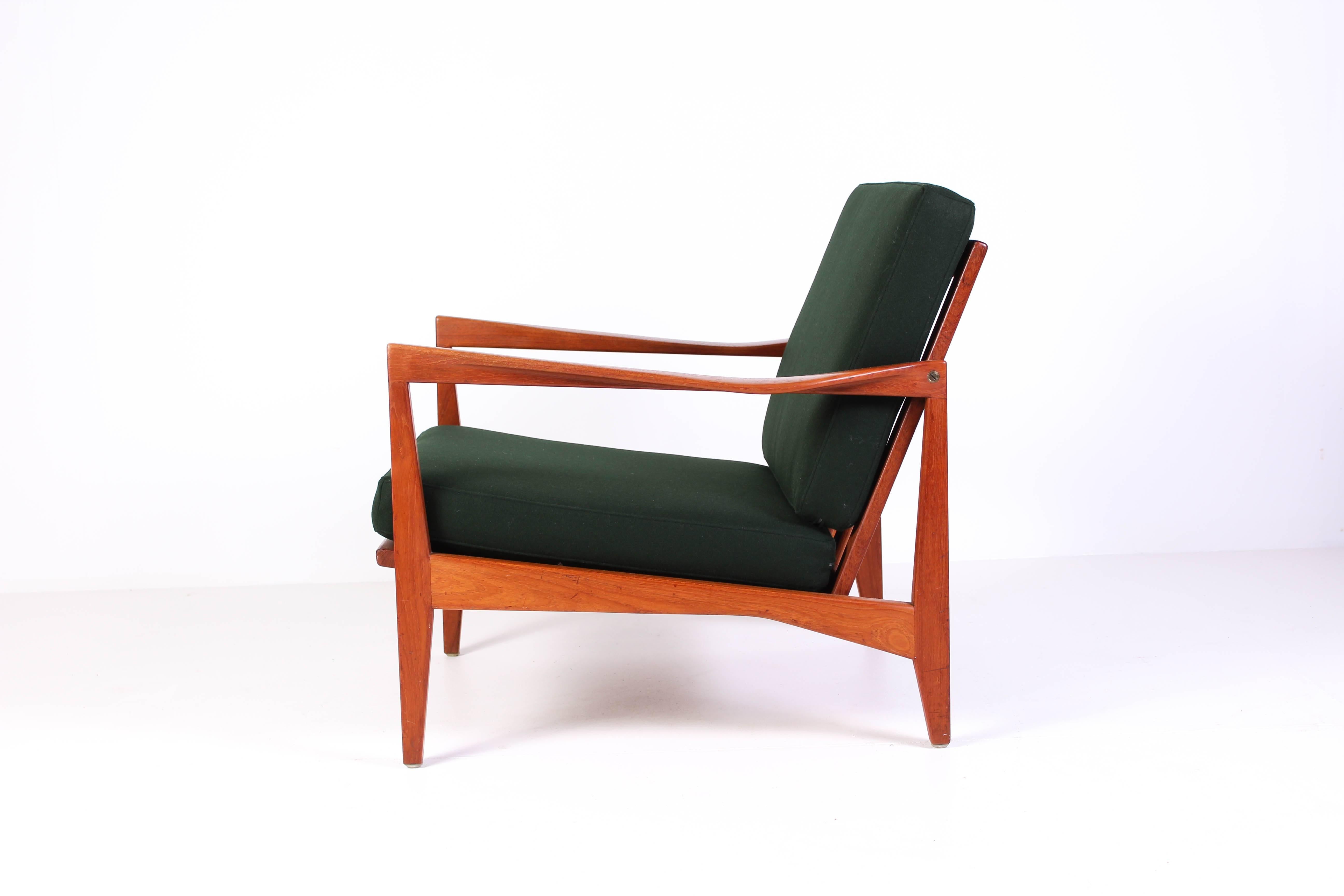 Midcentury teak easy chair by Swedish designer Svante Skogh. The chair has several nice details such as twisted armrests, brass fittings and sculptured back. New cushions upholstered with green 100% wool fabric by the Swedish producer Klippan