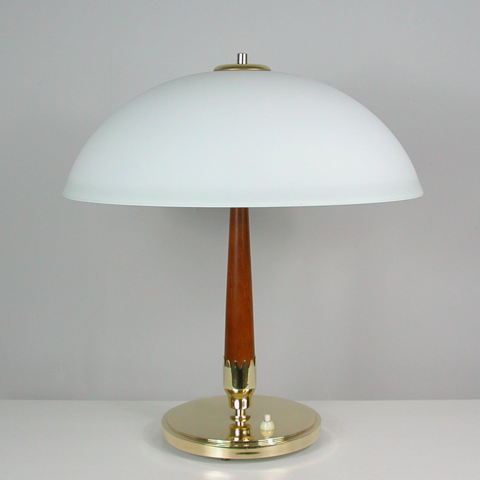 This large and elegant Scandinavian modernist table lamp was designed and manufactured in Sweden in the 1950s by Bohlmarks (model no. 15520). It features a brass base, teak lamp stem and a dome shaped frosted opaline lampshade and requires two E27