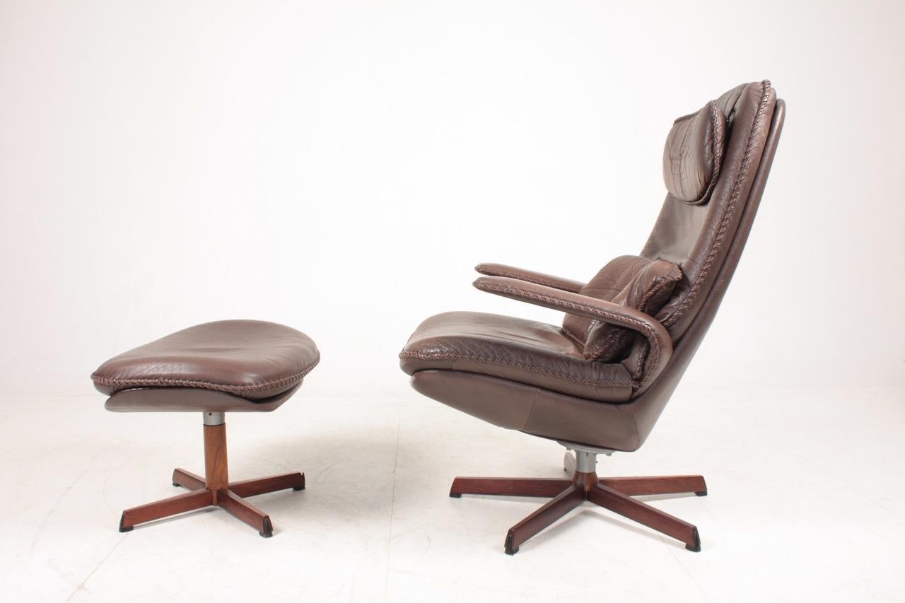 Great looking and very comfortable swivel chair with matching foot stool in patinated leather, designed by Danish architects Madsen & Schubell in the 1960s. Great original condition.