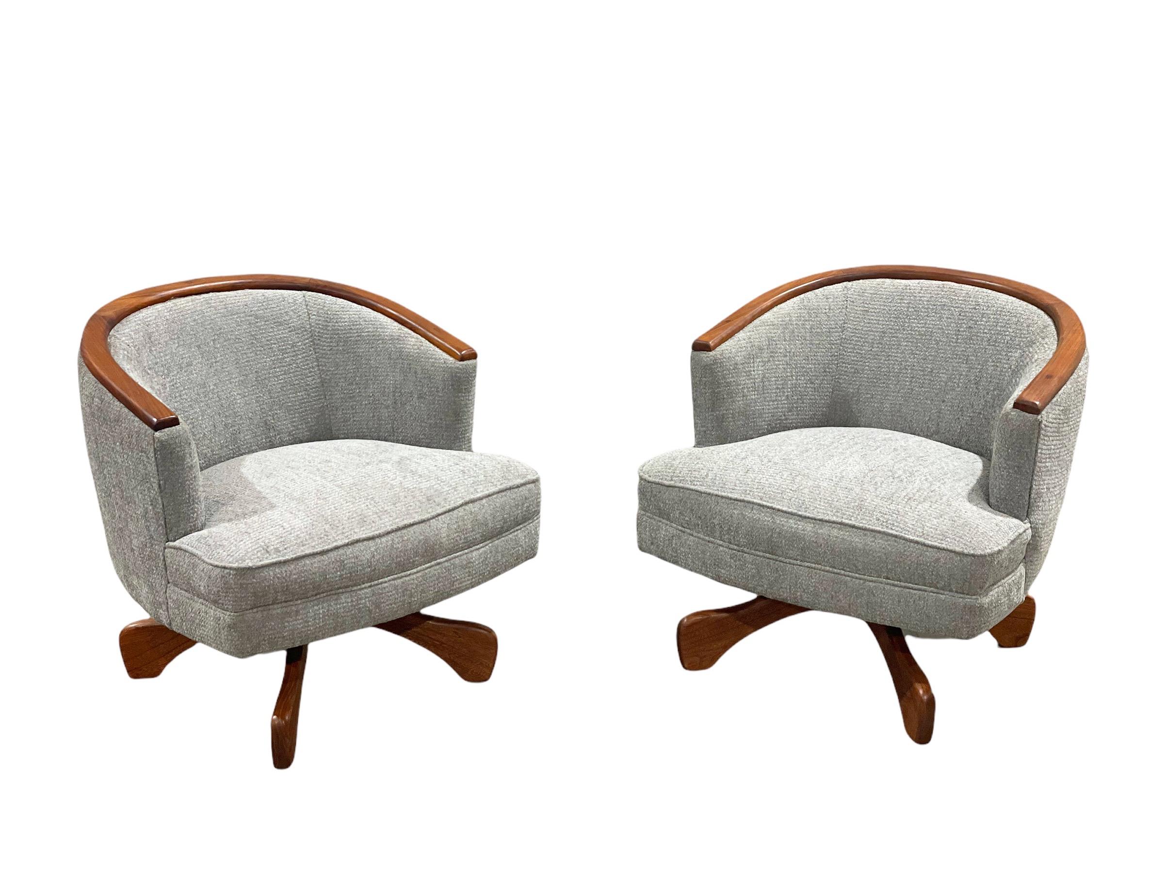 Pair of Mid-Century Modern swivel club barrel chairs after Adrian Pearsall. Unique and refined design with a skosh of fun flair. Completely restored by our team of in-house artisans. Solid walnut paddle bases and arm detail have been fully