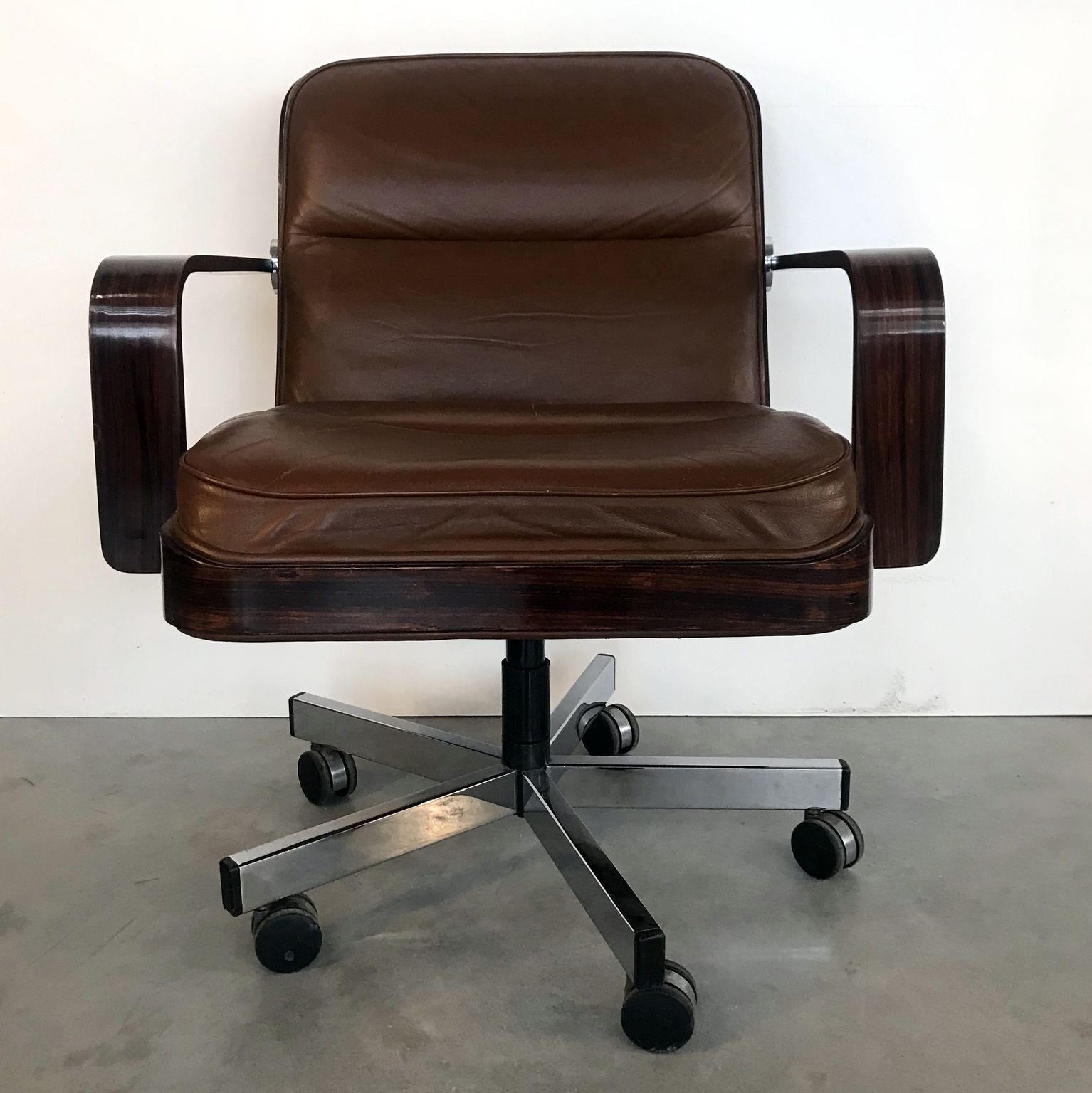 Beautiful chair is made of a brown leather seating with Macassar ebony frame and armrests on swivel chrome leg. Upholstered with original material.